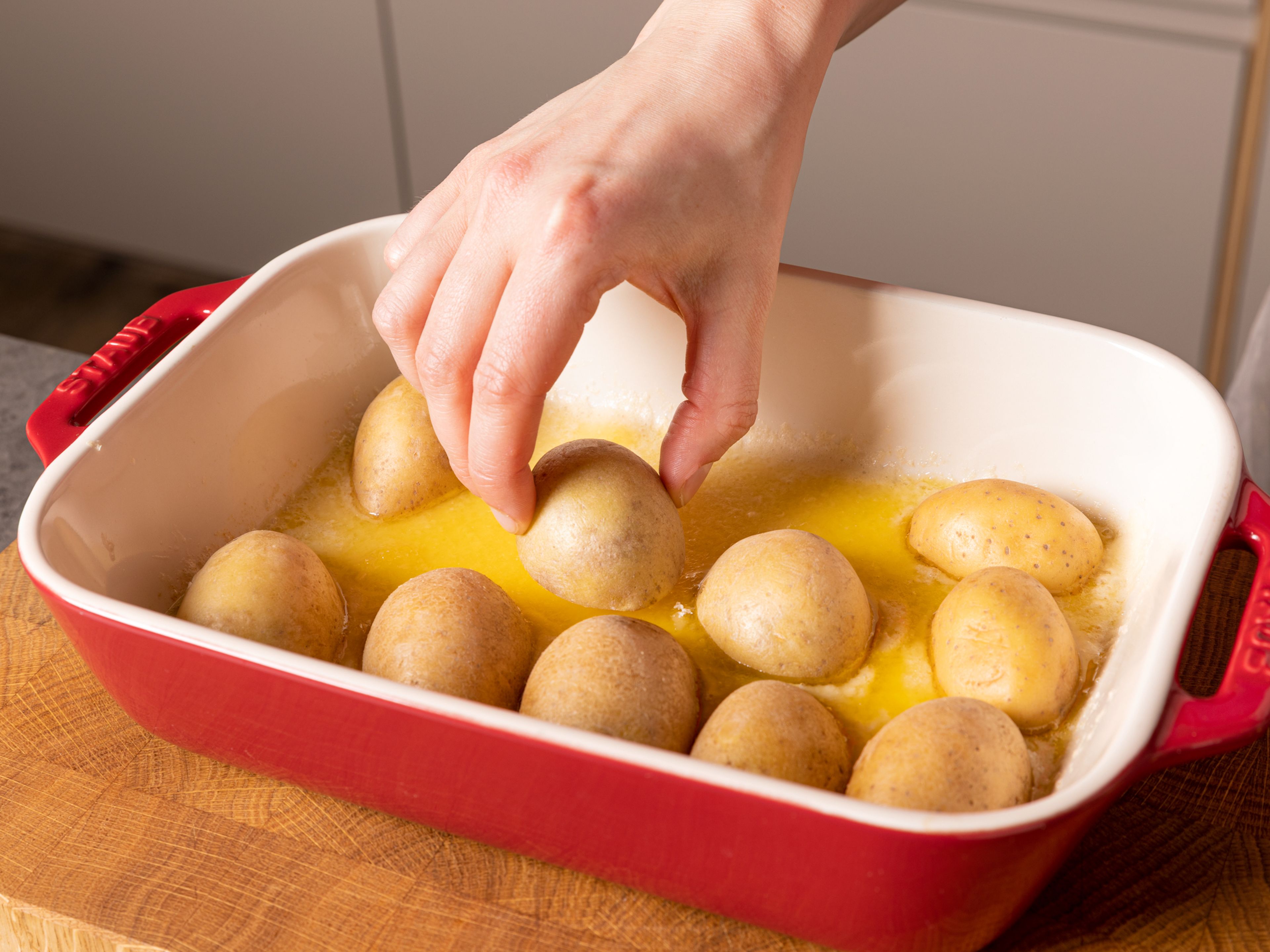 Butter in die heiße Auflaufform geben und schmelzen lassen. Dann ¾ des Parmesans gleichmäßig auf den Boden der Form geben. Die Kartoffeln mit der Schnittfläche nach unten darauf legen. Mit Salz und Pfeffer würzen und ca. 20 Min. backen.