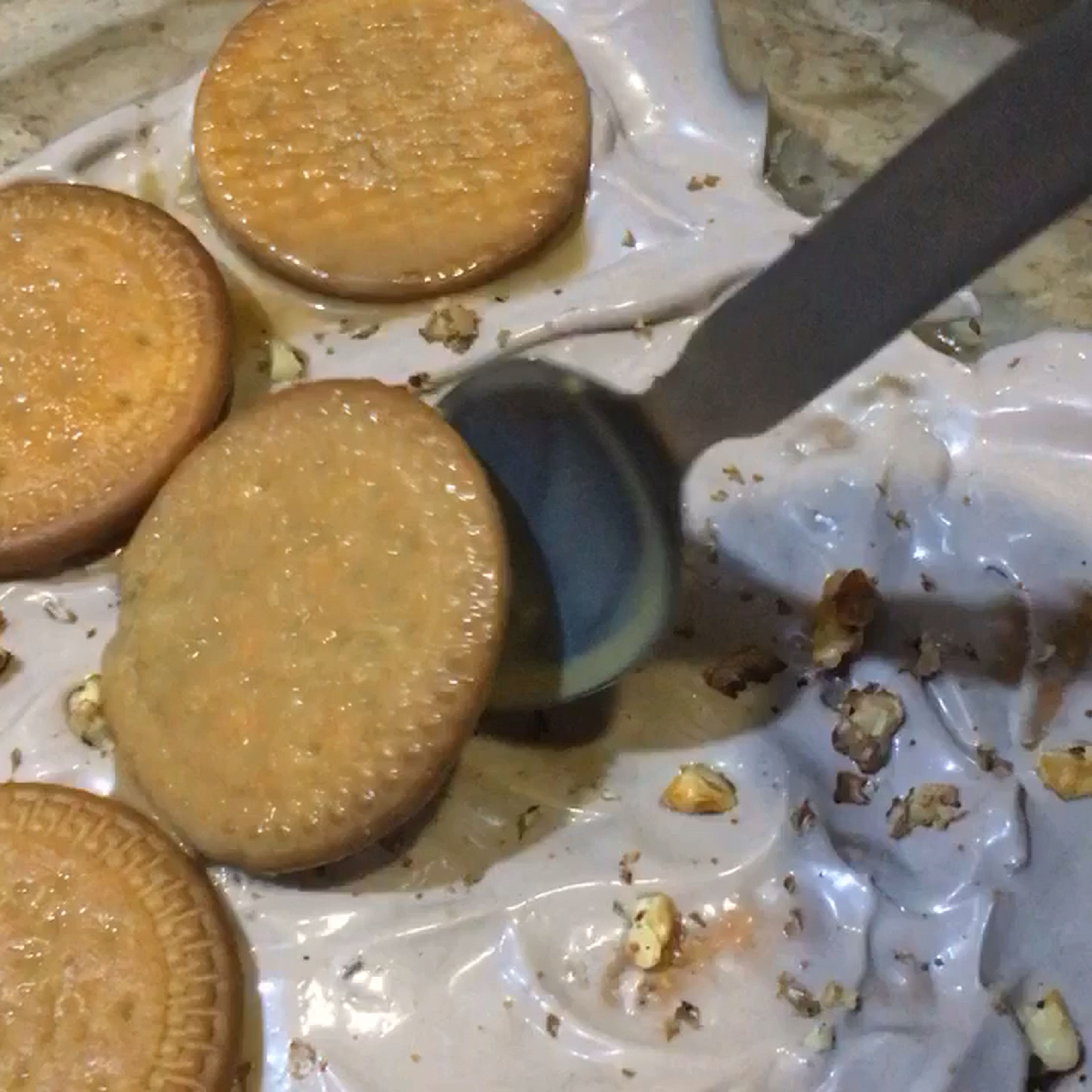 Start layering now. Take a Pyrex dish, dip biscuits in warm milk and start placing them at the bottom of the dish, after completing one layer, add a layer of whipped cream. Two layers would be enough. Top it with roasted walnuts and your cold cake is ready!