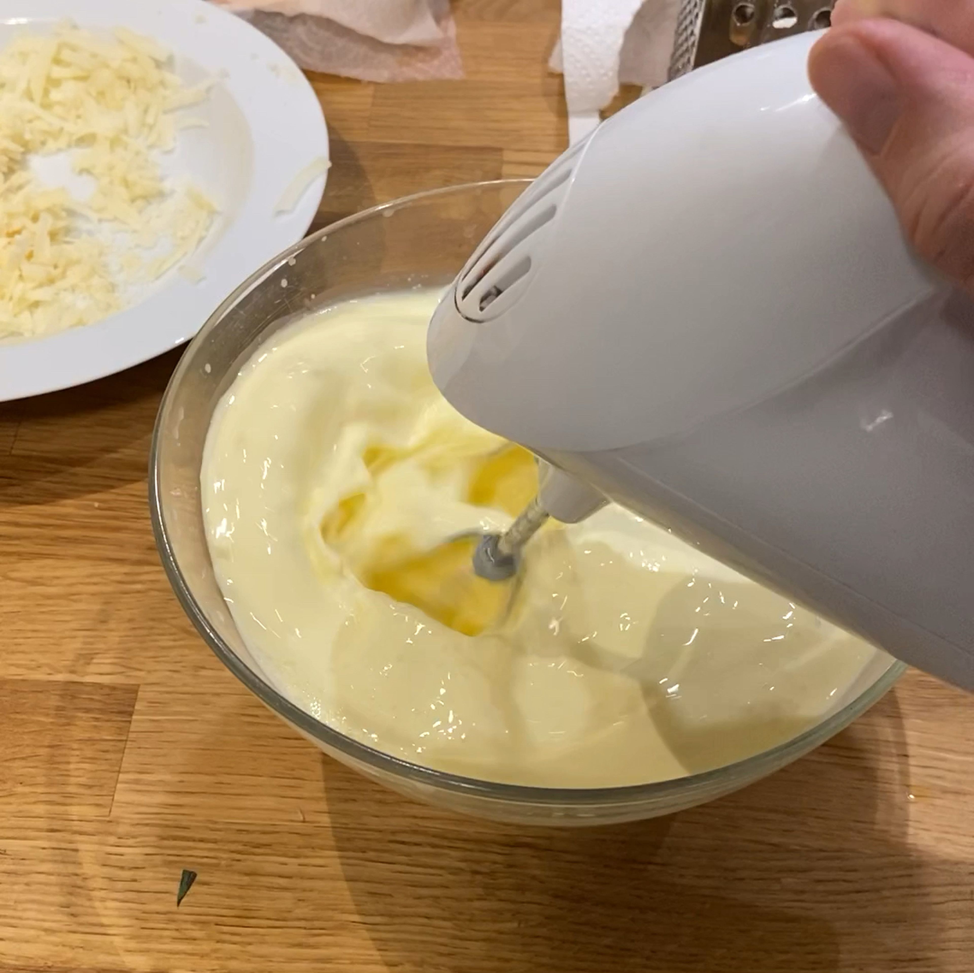 In einer Schüssel die Eier, Creme fraiche, Sahne, und die Hälfte des Käse mit dem Mixstab mischen. Mit den Gewürzen abschmecken.