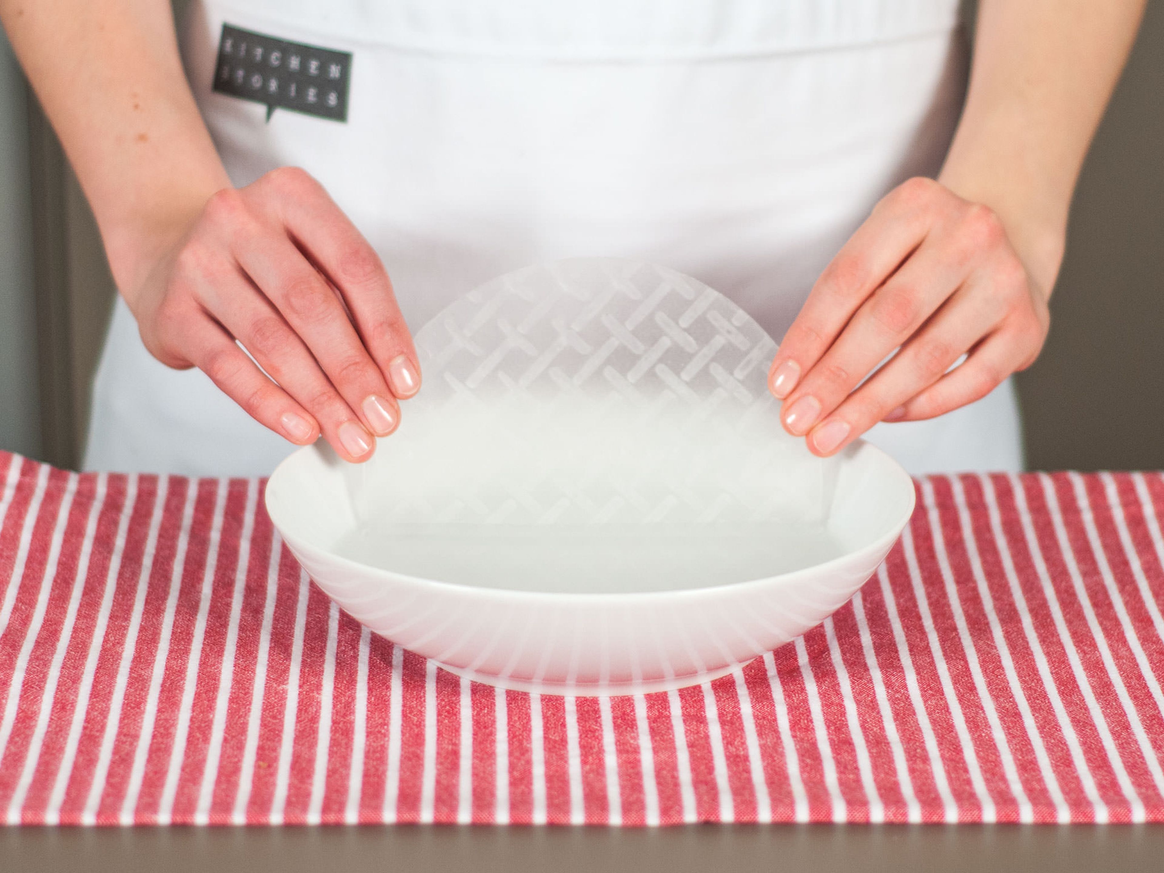 Reispapier gleichmäßig mit Wasser bedecken und ca. 1 Min. einweichen lassen. Leicht schütteln, damit das überschüssige Wasser abtropft. Auf einem Teller oder Schneidebrett beiseitestellen.