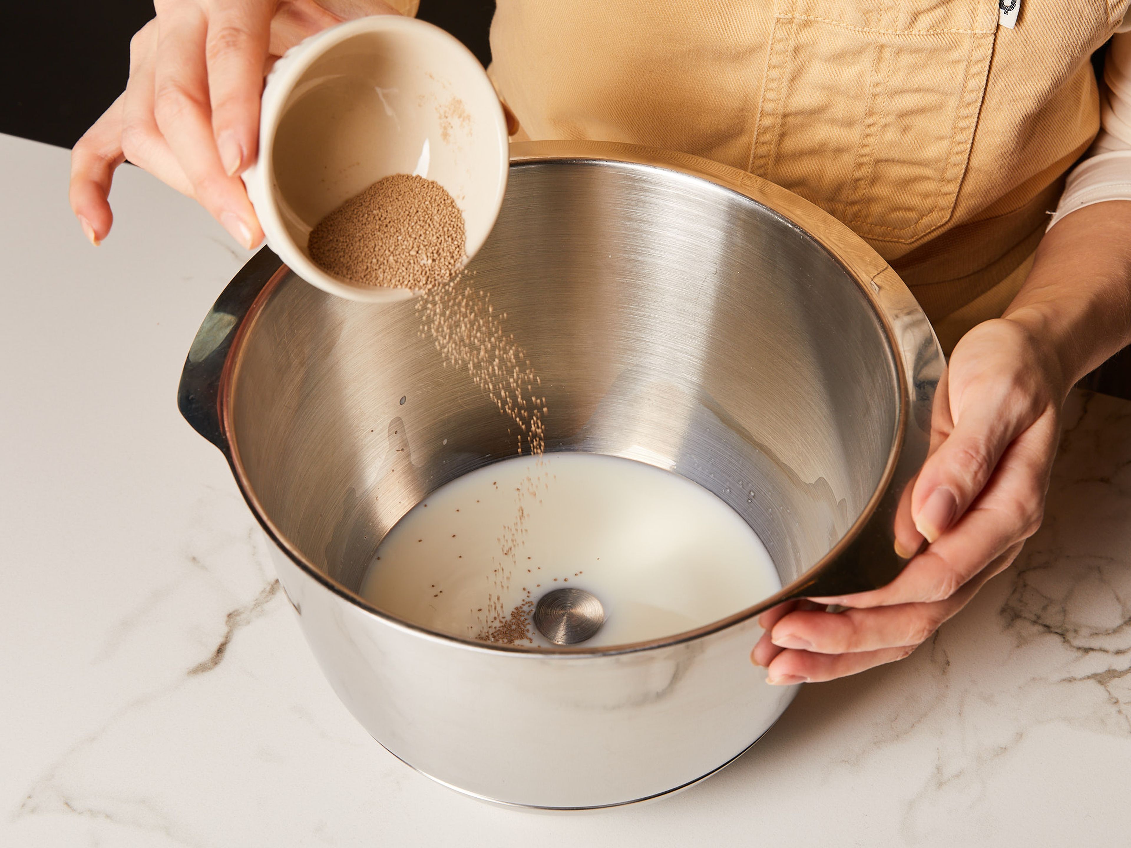 Hefe und lauwarme Milch in einer Rührschüssel miteinander verrühren, abdecken und ca. 10 Min. beiseitestellen, bis die Mischung beginnt zu schäumen.