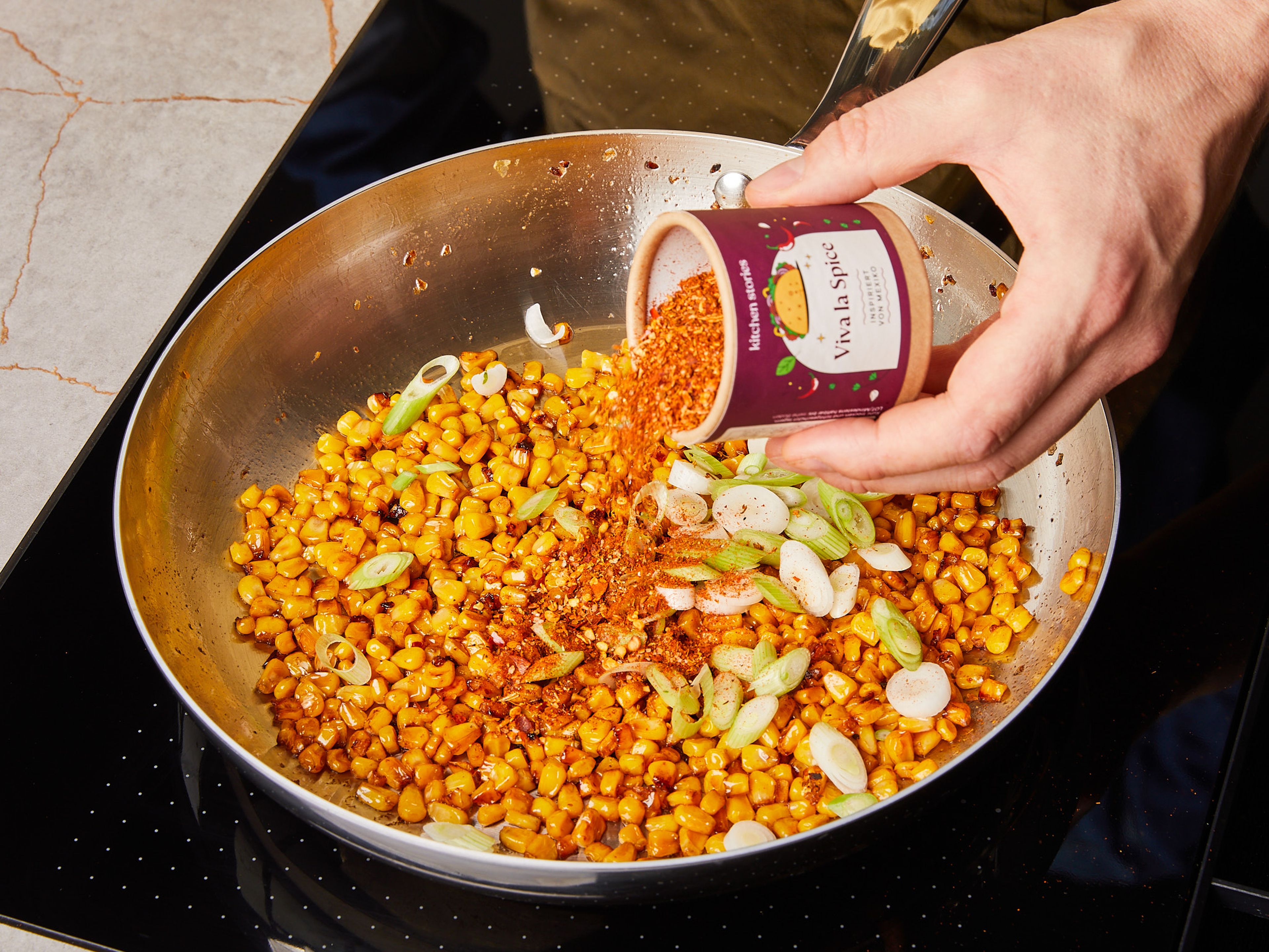 Remove all but approx. 2 tablespoons of the excess fat from the pan. Increase heat again and add the drained corn. Fry for approx. 5–6 min. stirring occasionally, until the kernels turn golden brown. Remove some of the corn kernels from the pan and set aside to garnish later. Add the scallion whites and VIVA LA SPICE seasoning, stir briefly until aromatic, then add the pan contents to the pasta.