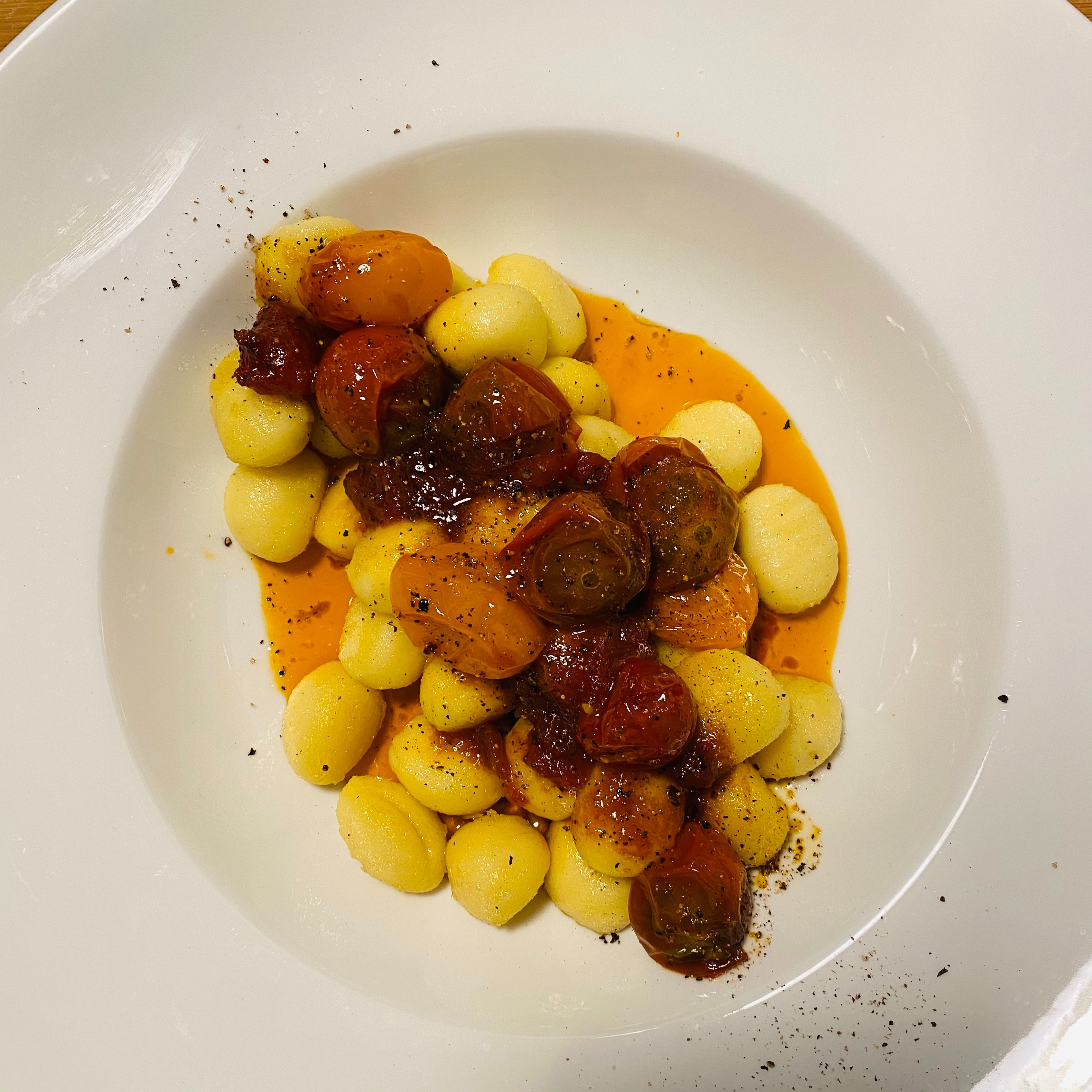 Place the gnocchi on a nice plate. Top with the roasted tomato-garlic mix. Spoon the aromatic sweet & spicy oil over the dish. Finish with a good grind of pepper, sprinkle with salt, and serve.