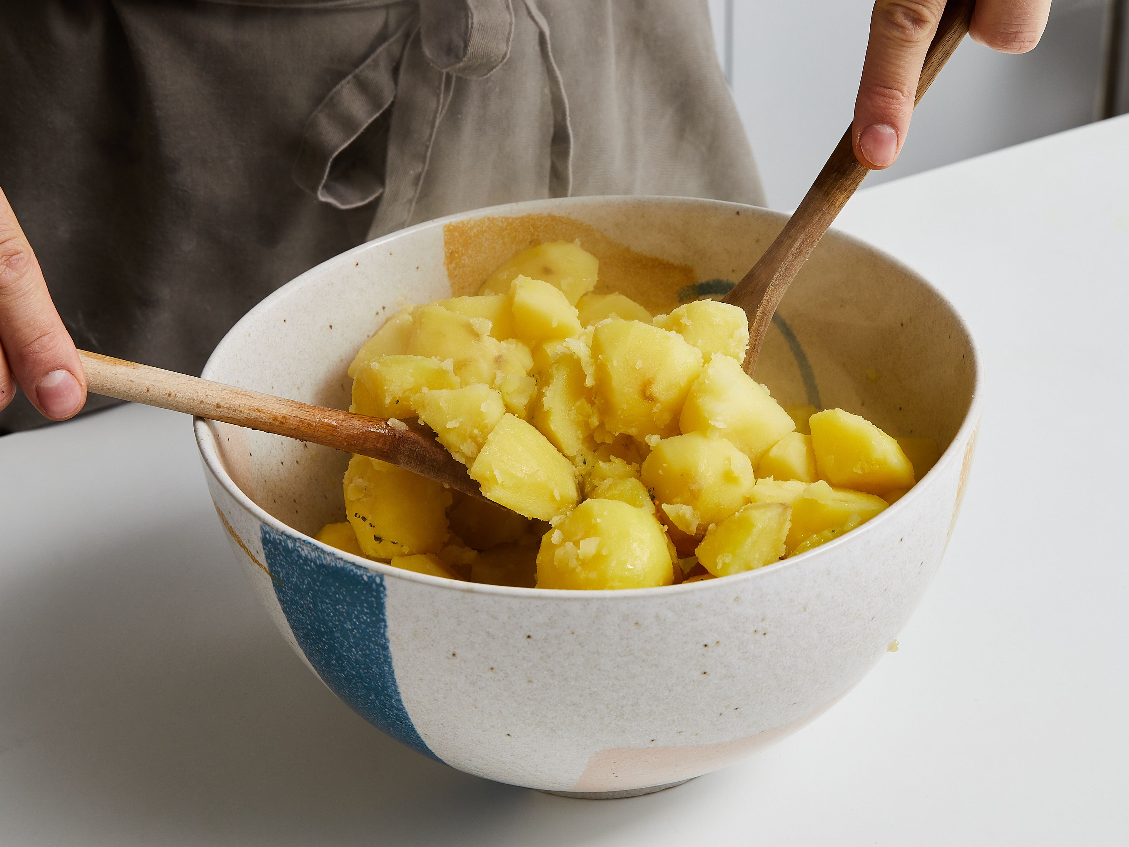 When potatoes are cooked, carefully drain them and put them back in the pot for about 30 seconds, to allow excess moisture to evaporate. Add potato pieces to the bowl with the oil, season with a little more salt and pepper, and toss until a thin layer of the mushy surface has formed.