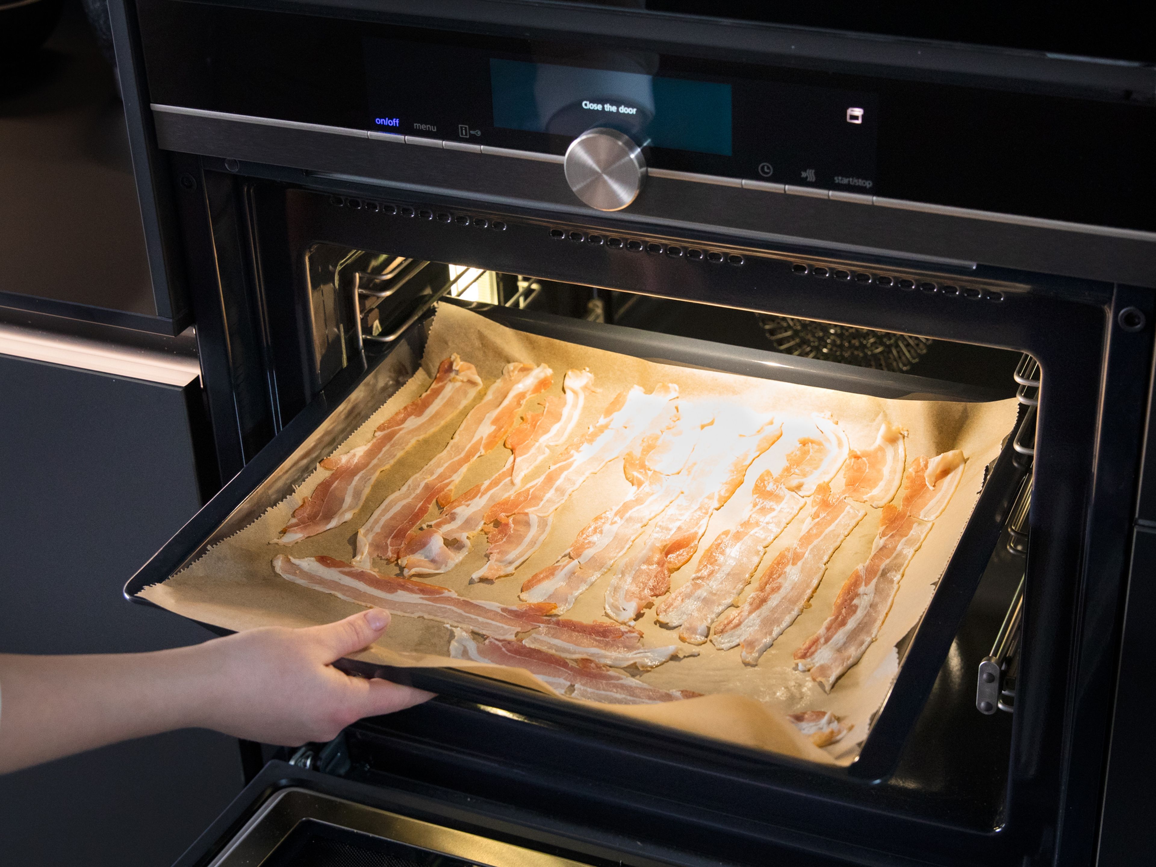 Den Ofen auf 160°C vorheizen. Bacon auf ein Backblech mit ausgelegtem Backpapier legen und im Ofen für ca. 20 min. backen bis er knusprig ist.