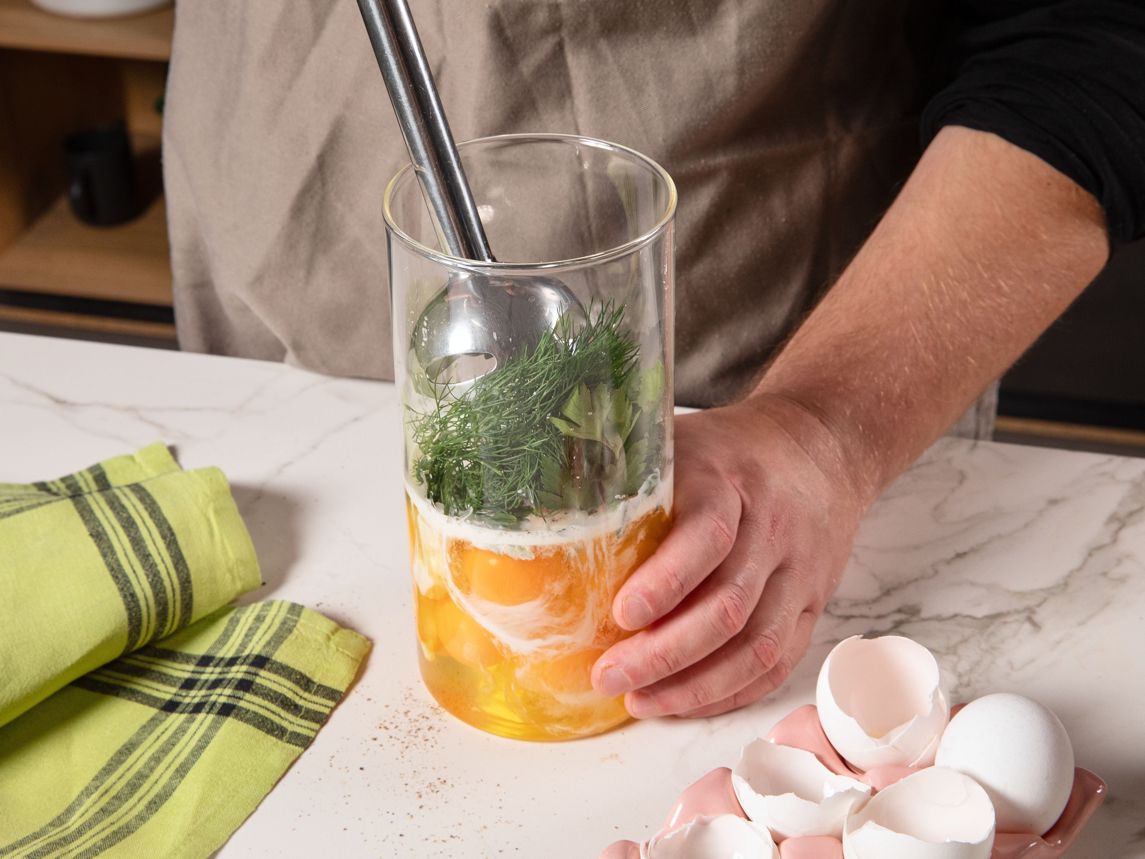 Während das Gemüse im Ofen gart, die Eiermischung zubereiten. Die Eier aufschlagen und mit der Hälfte der Kräuter, Sahne, Parmesan, etwas Salz und Pfeffer in einem hohen Gefäß mit einem Pürierstab glatt pürieren.