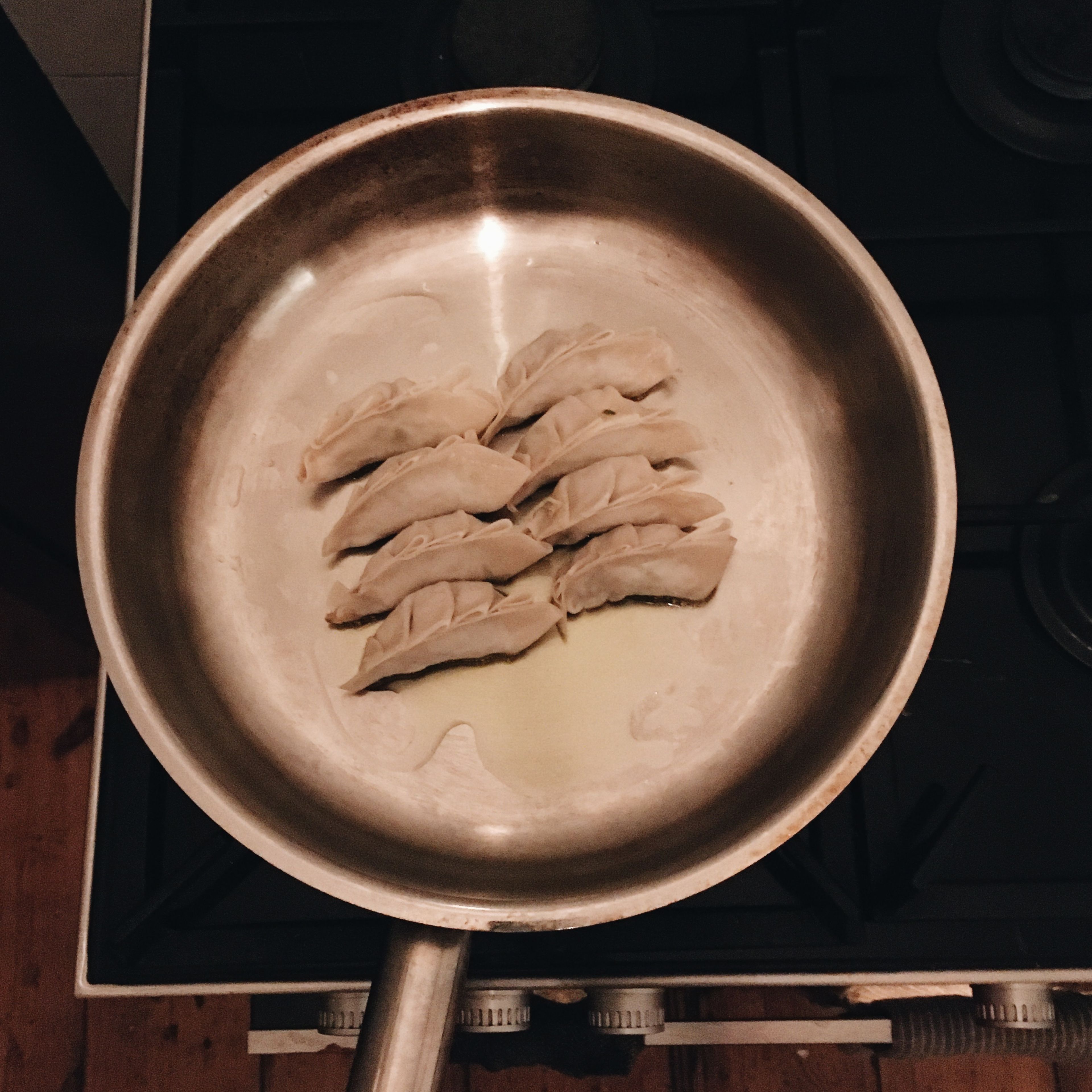 Heat oil in a large frying pan. Once heated, place the gyoza in a single layer, in two rows. Cook until the bottom of the gyoza is lightly golden, roughly 3 min.