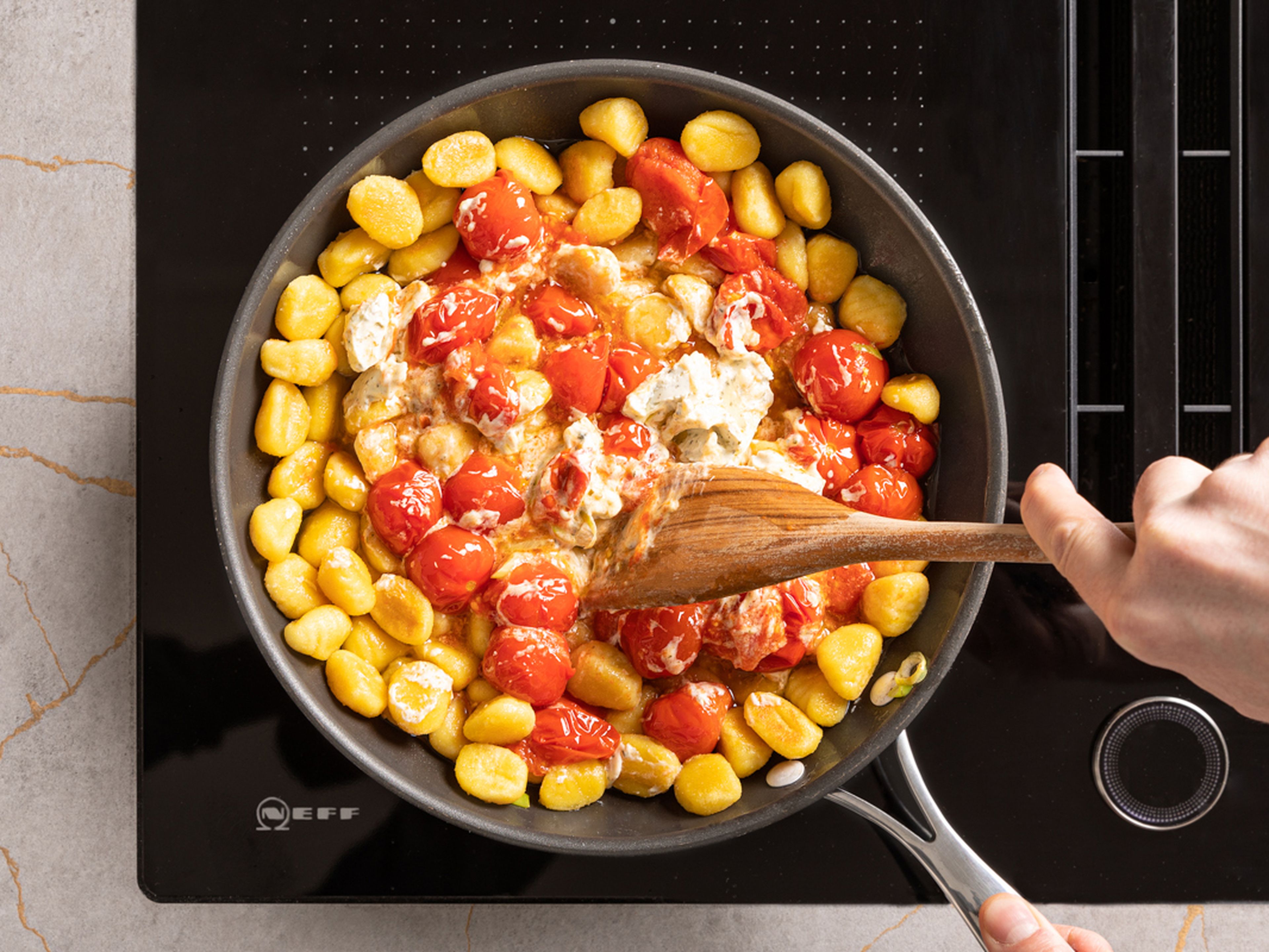 Heat some oil in a large frying pan and fry the gnocchi in it for approx. 6–8 min. until golden brown. Add burst cherry tomatoes and some herb cream cheese to the gnocchi in the pan, toss and season with salt and pepper.