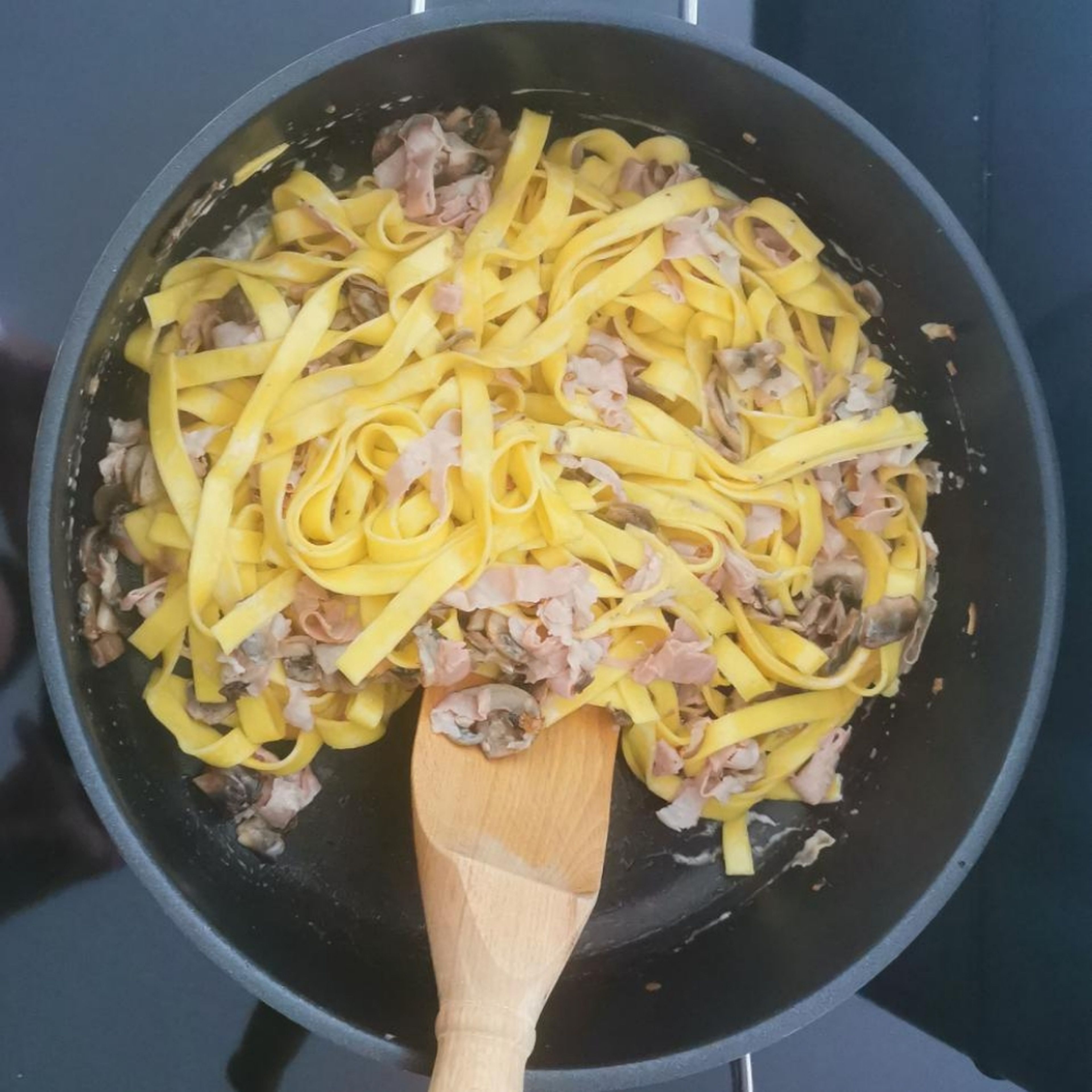 Fertige Tagliatelle abgießen und in der Pfanne mit dem Schinken und den Champignons vermengen. Anschließend Sahne hinzugeben und nochmal durchrühren.