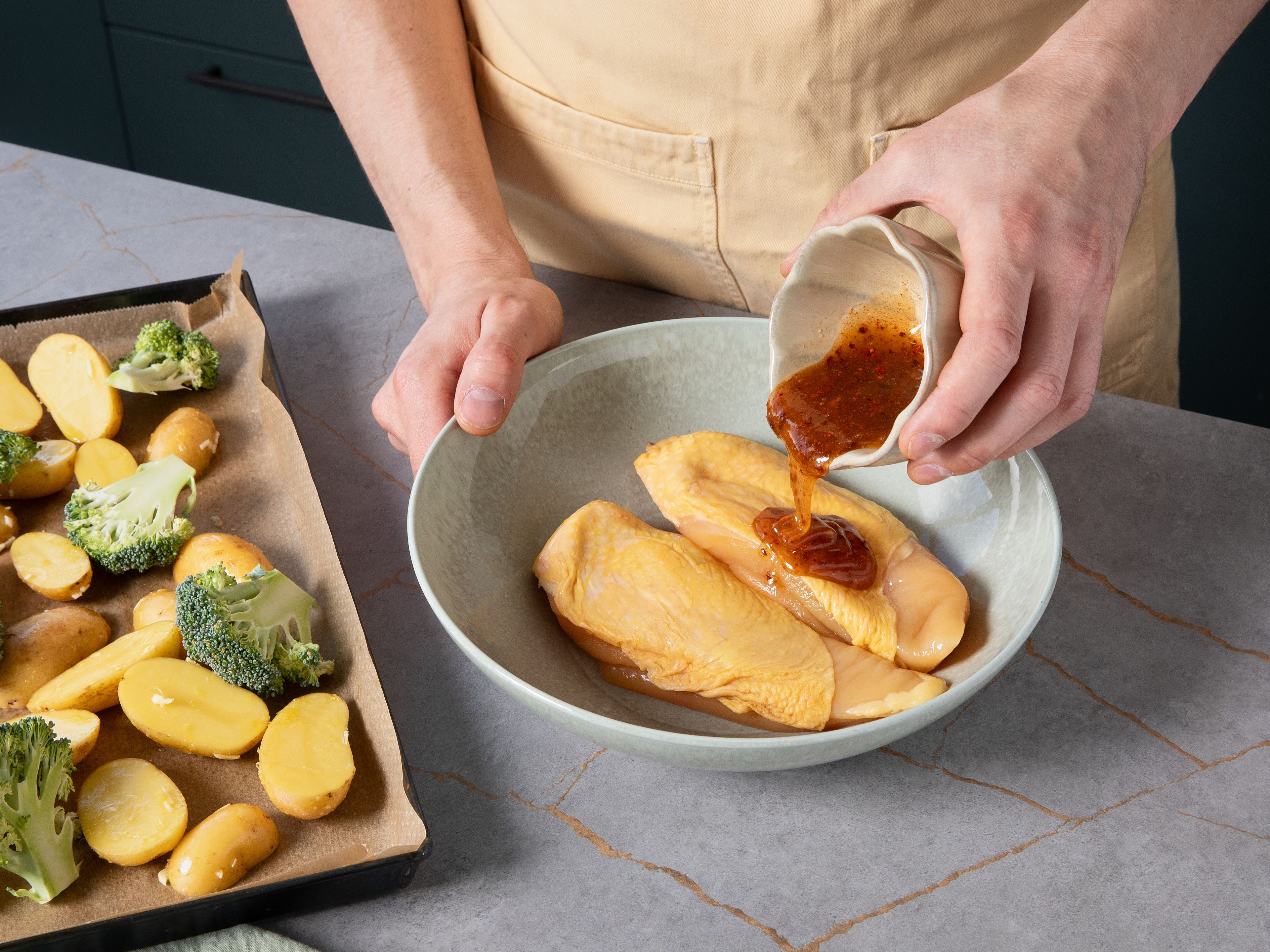 Hähnchen mit Küchenpapier trocken tupfen. In einer separaten Schüssel Olivenöl mit Honig, Paprikapulver, Chiliflocken, Salz und Pfeffer verrühren. Das Hähnchen rundum mit der Marinade einreiben und auf das Backblech zu Kartoffeln und Brokkoli legen. Auf mittlerer Schiene ca. 35–40 Min. im Ofen backen, bis das Hähnchen goldbraun und durchgegart ist.