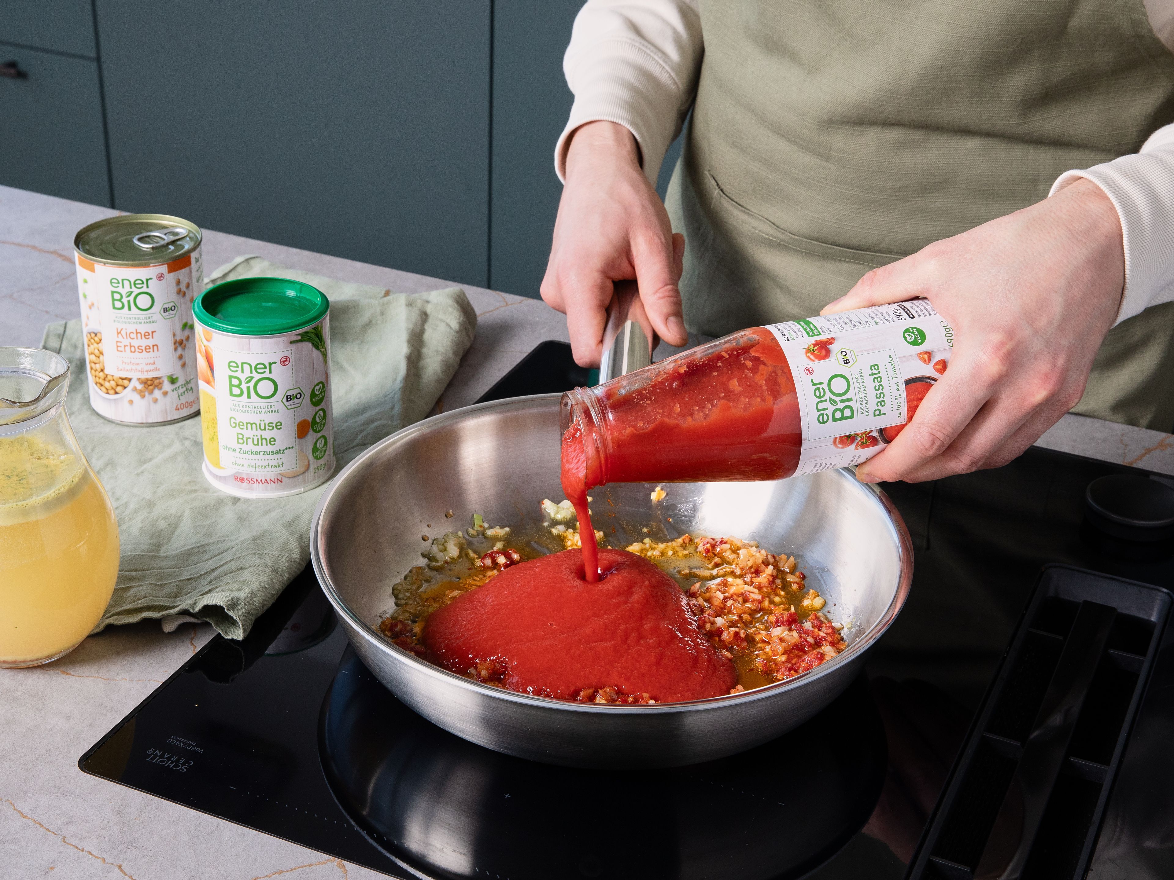 In der Zwischenzeit Zwiebel schälen und fein würfeln. In einer großen Pfanne etwas enerBiO Natives Olivenöl extra erhitzen und die Zwiebel darin bei mittlerer Hitze glasig dünsten. Das enerBiO Tomatenmark einrühren und kurz anrösten. Mit enerBiO Passata und enerBiO Gemüsebrühe ablöschen und aufkochen lassen. Die enerBiO Kichererbsen abspülen und abtropfen lassen und hinzufügen. Die Soße bei niedriger Hitze köcheln lassen, bis sie dickflüssig und kräftig ist. Mit Salz und Pfeffer abschmecken. Währenddessen die Pasta kochen.