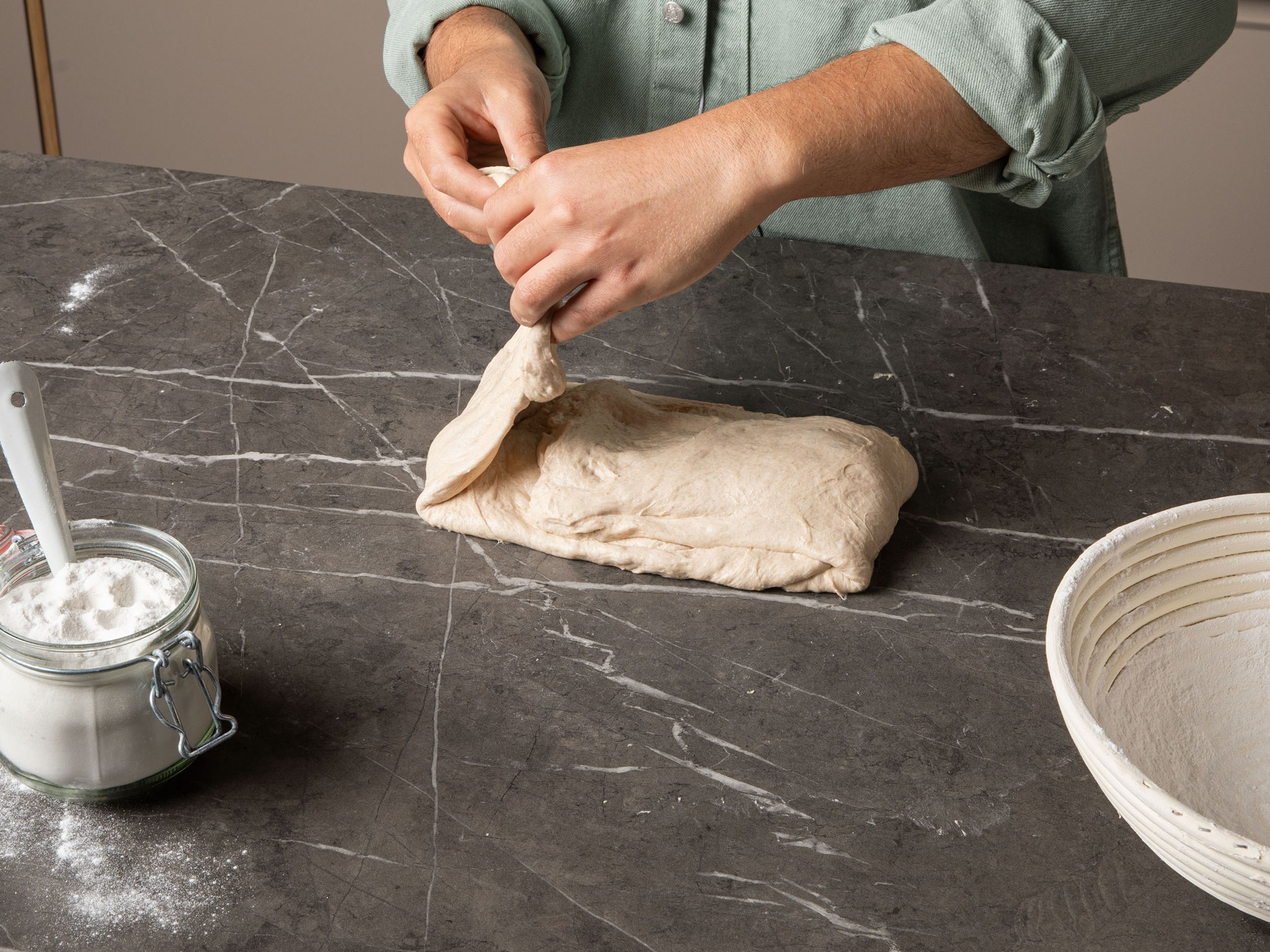 Perform a final stretch and fold (“lamination fold”). Use wet hands to transfer the dough to a lightly wet surface, flatten the dough with your hands and gently stretch it out into a thin circle by pulling continuously around the circumference of the dough. Fold the dough for its final shape by grabbing it from the end closest to you, pull it towards you and fold it into the middle, then fold the opposite end over it. Do the same with the other sides. Grab each corner and gently stretch them into the middle. Flip the dough over so the seam-side is on the counter and begin building tension on the surface of the dough by pulling it towards you in a circular motion. Do this a few times until the dough has a tight surface, wet your hands whenever necessary. For the longer bulk fermentation, transfer the dough back to the bowl, cover it with a damp kitchen towel and let it rise until doubled in size, approx. 4-12 hrs. The amount of time it takes depends on how active your starter was as well as your environment (alternatively, let the dough rise for 1 hr. and then pop it in the fridge and finish the process the following day).