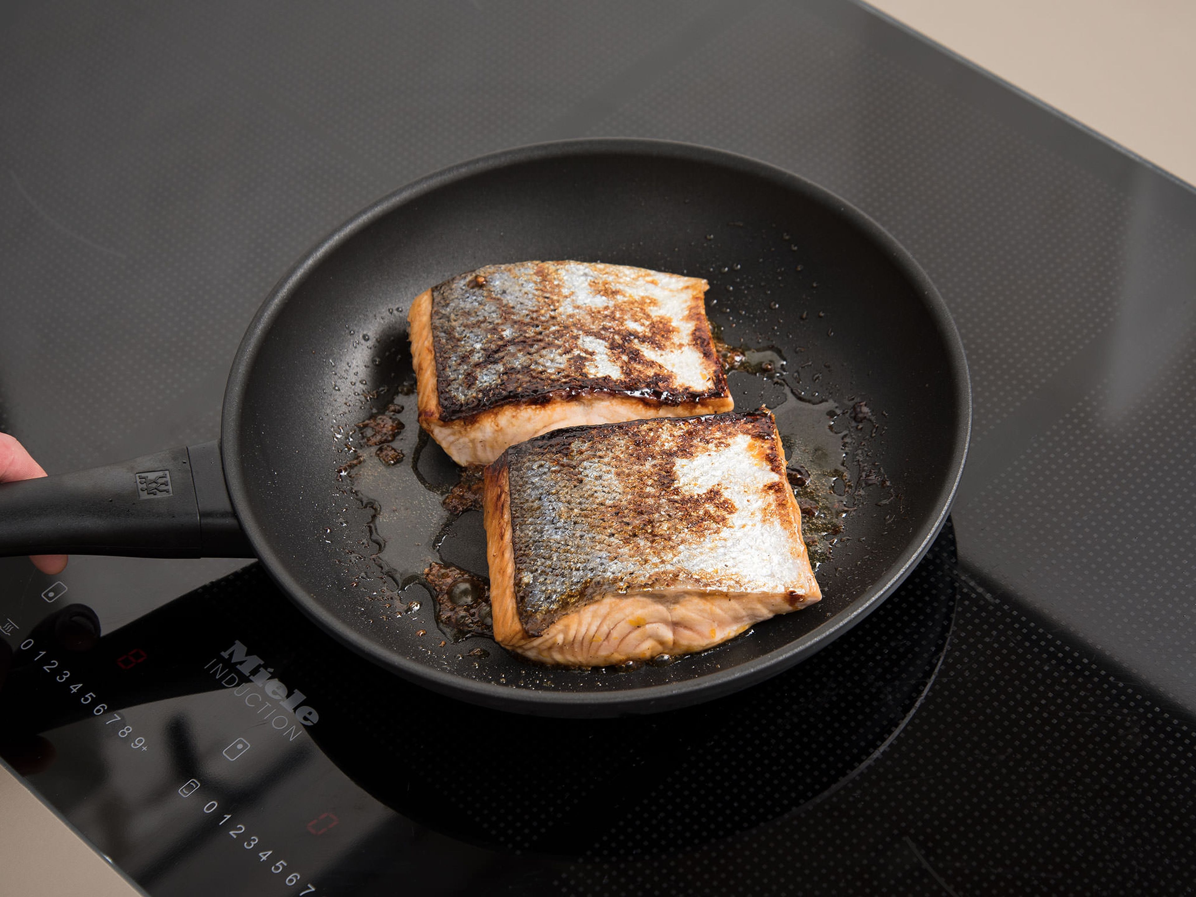Heat the rest of the olive oil in a frying pan over medium-high heat, and fry the salmon skin side down for approx. 2 min. Flip the fillets over and brush with remaining syrup. Cook for another 3 - 4 min. or until cooked to desired level of doneness.