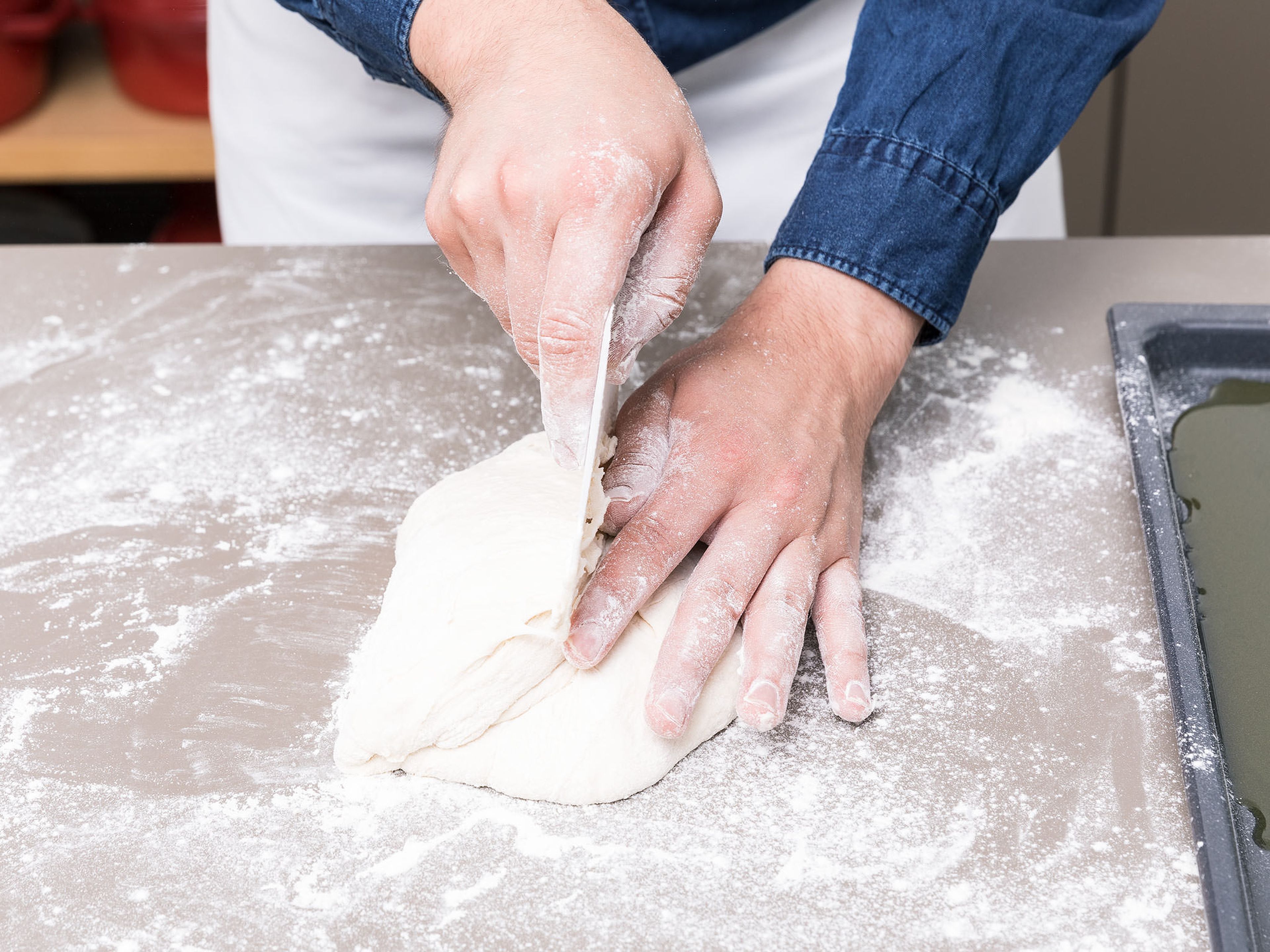 Preheat the oven to 230°C/450°F and put an empty baking sheet in the bottom position. Transfer dough to a floured work surface and sprinkle with more flour. Cut the dough in half and fold each piece into thirds, then half, patting and shaping into a loaf as you go.