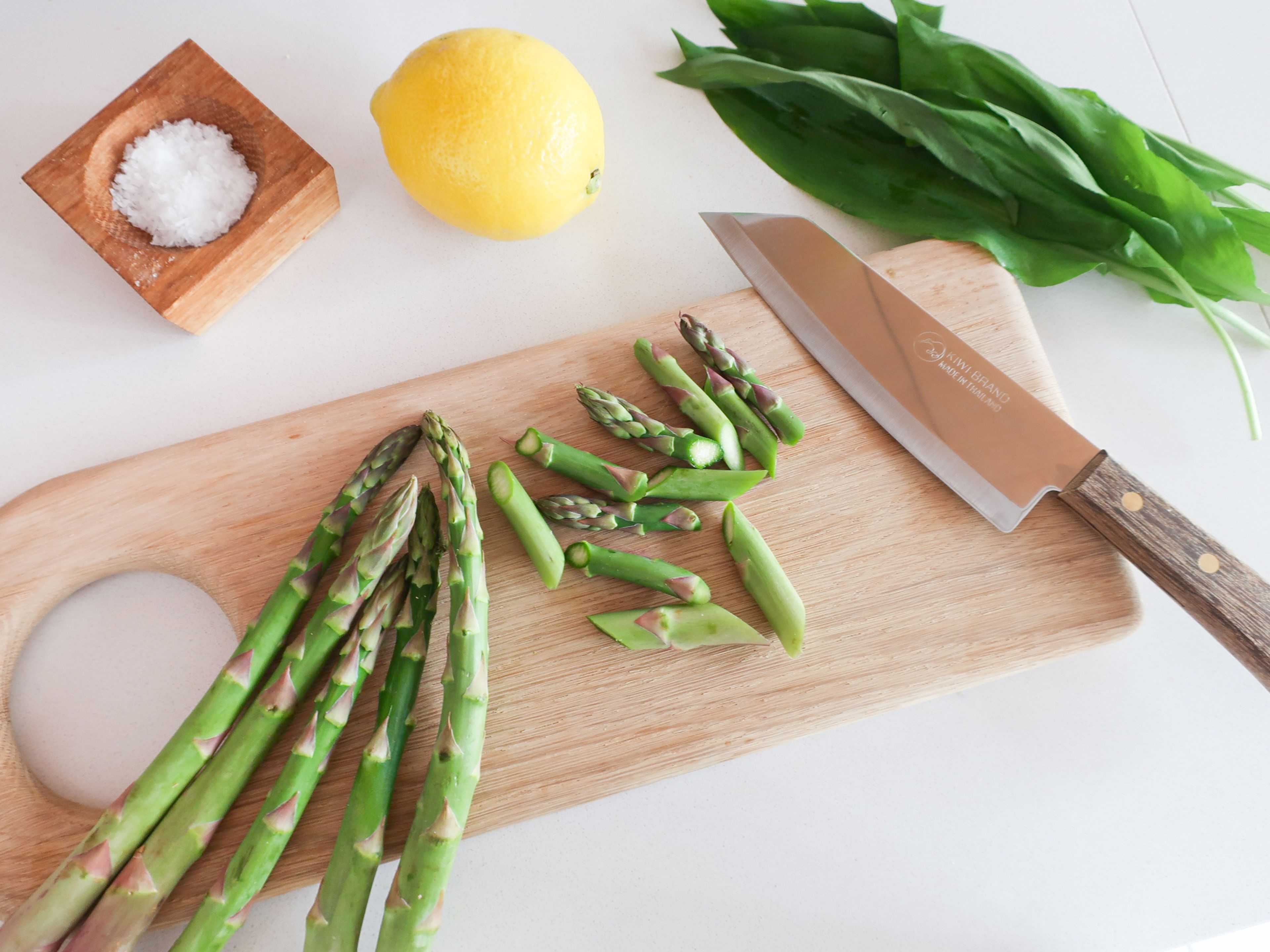 Remove stems from wild garlic and set leaves aside. Peel the onion, dice finely and set aside. Remove the woody ends of the asparagus. Slice off the asparagus tips and slice the stems into bite-sized pieces. Zest the lemon with a fine grater.