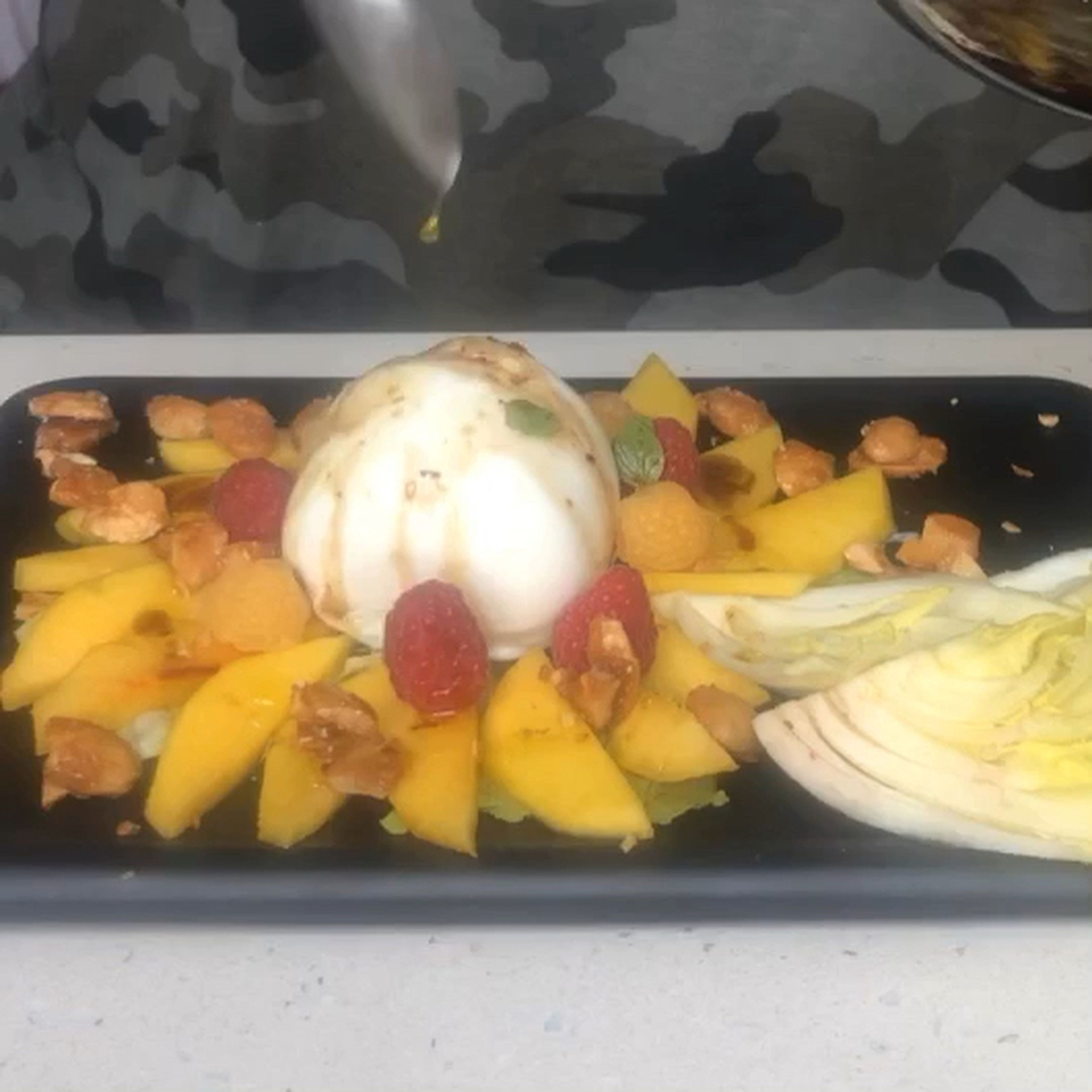 Start plating the design you like. For example you put the slices of peach in form to create a flower in the middle of it the burrata decorated with raspberries and addible flowers topped with the sauce and Caramelised almonds