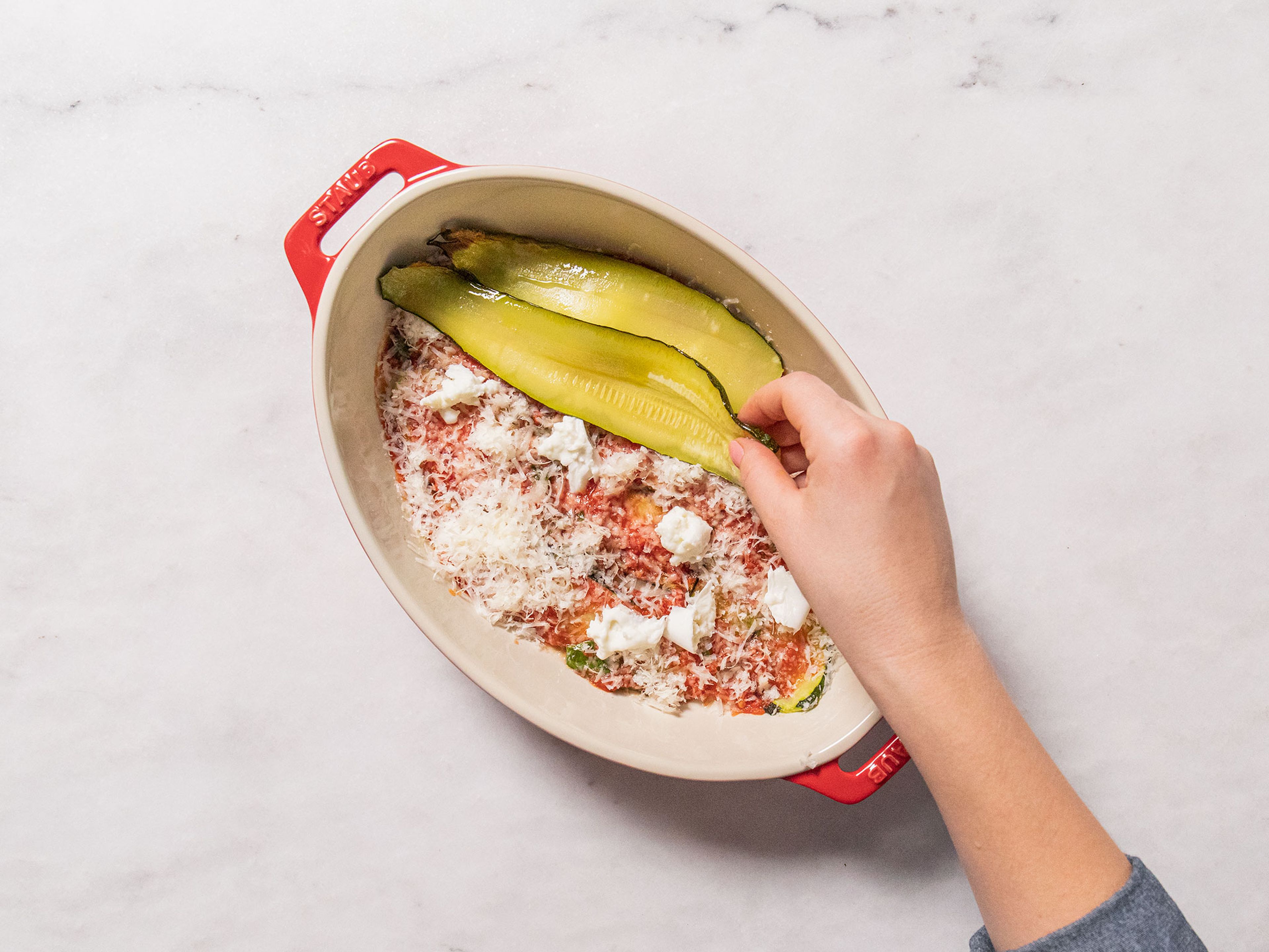 Cover the bottom of a baking dish with baked zucchini slices. Spread some tomato sauce over the zucchini, and top with Parmesan cheese and mozzarella. Repeat until all ingredients are gone, finishing the top layer with breadcrumbs.