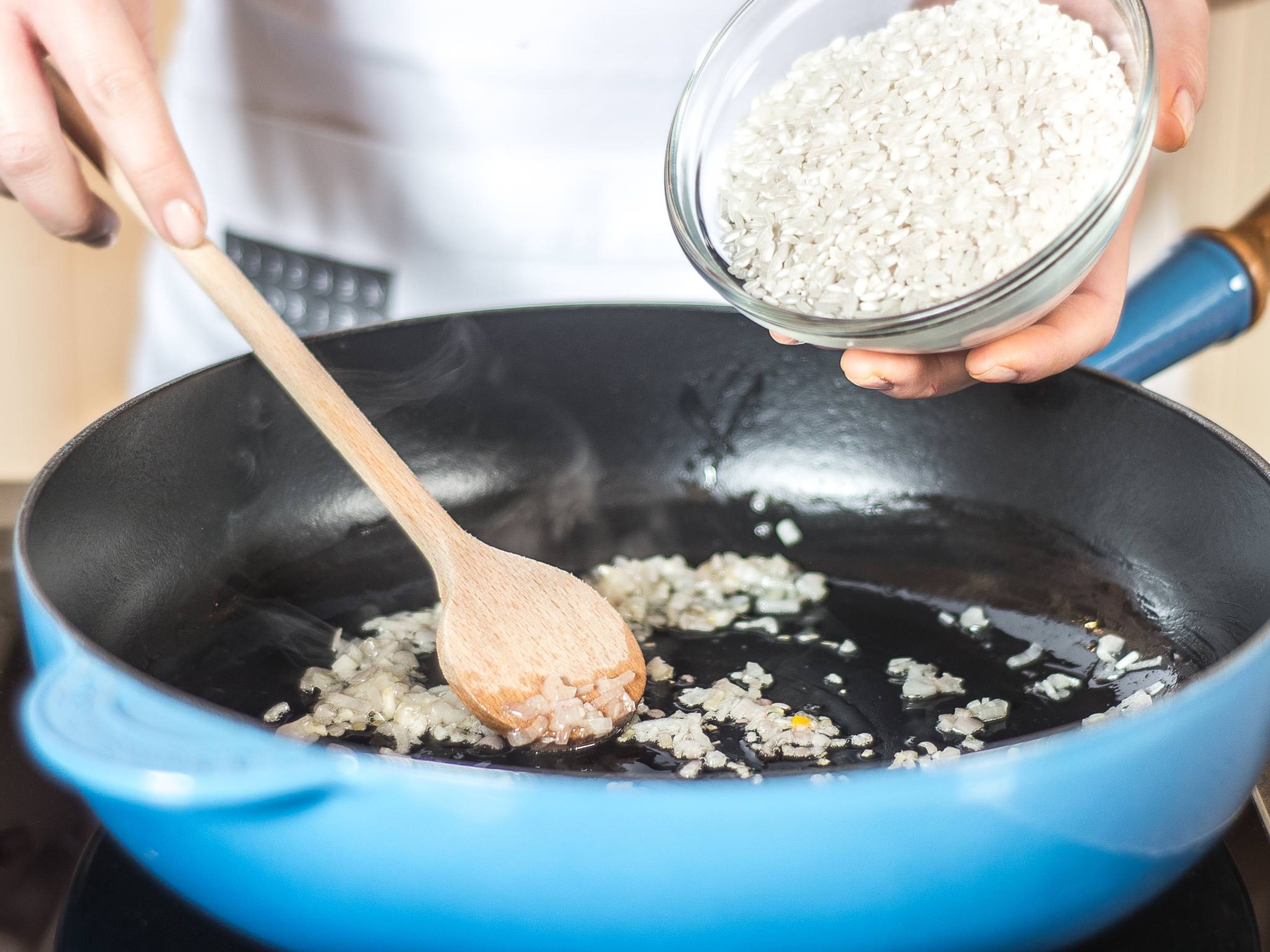 Zwiebeln und Knoblauch in etwas Pflanzenöl glasig anschwitzen. Anschließend den Risotto-Reis hinzugeben und ebenso leicht glasig anschwitzen.