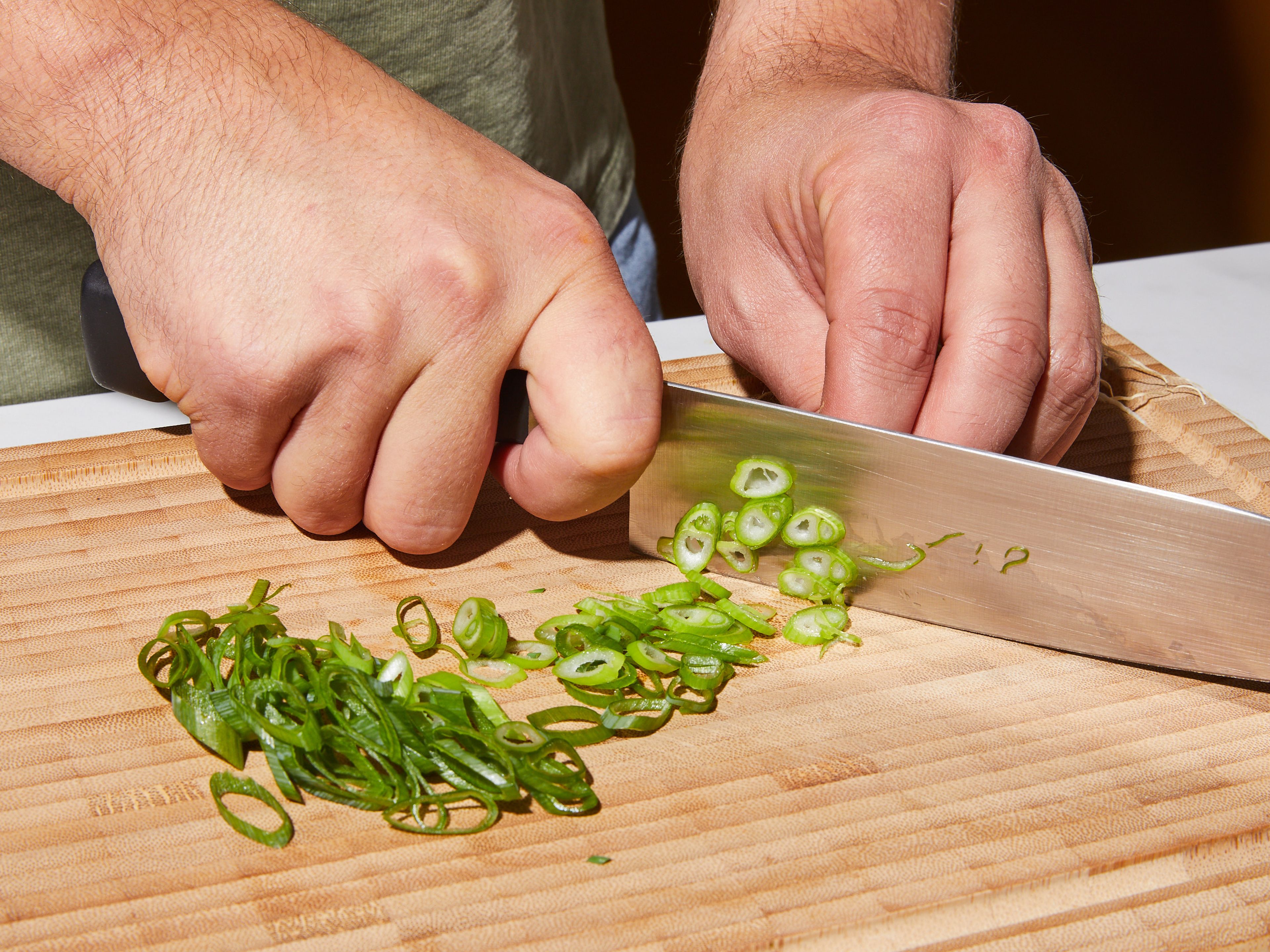 Zwiebel in feine Scheiben schneiden. Knoblauch und Ingwer hacken. Kimchi in breite Streifen schneiden, falls ganze Blätter verwendet werden. Frühlingszwiebeln zum Servieren in feine Scheiben schneiden.
