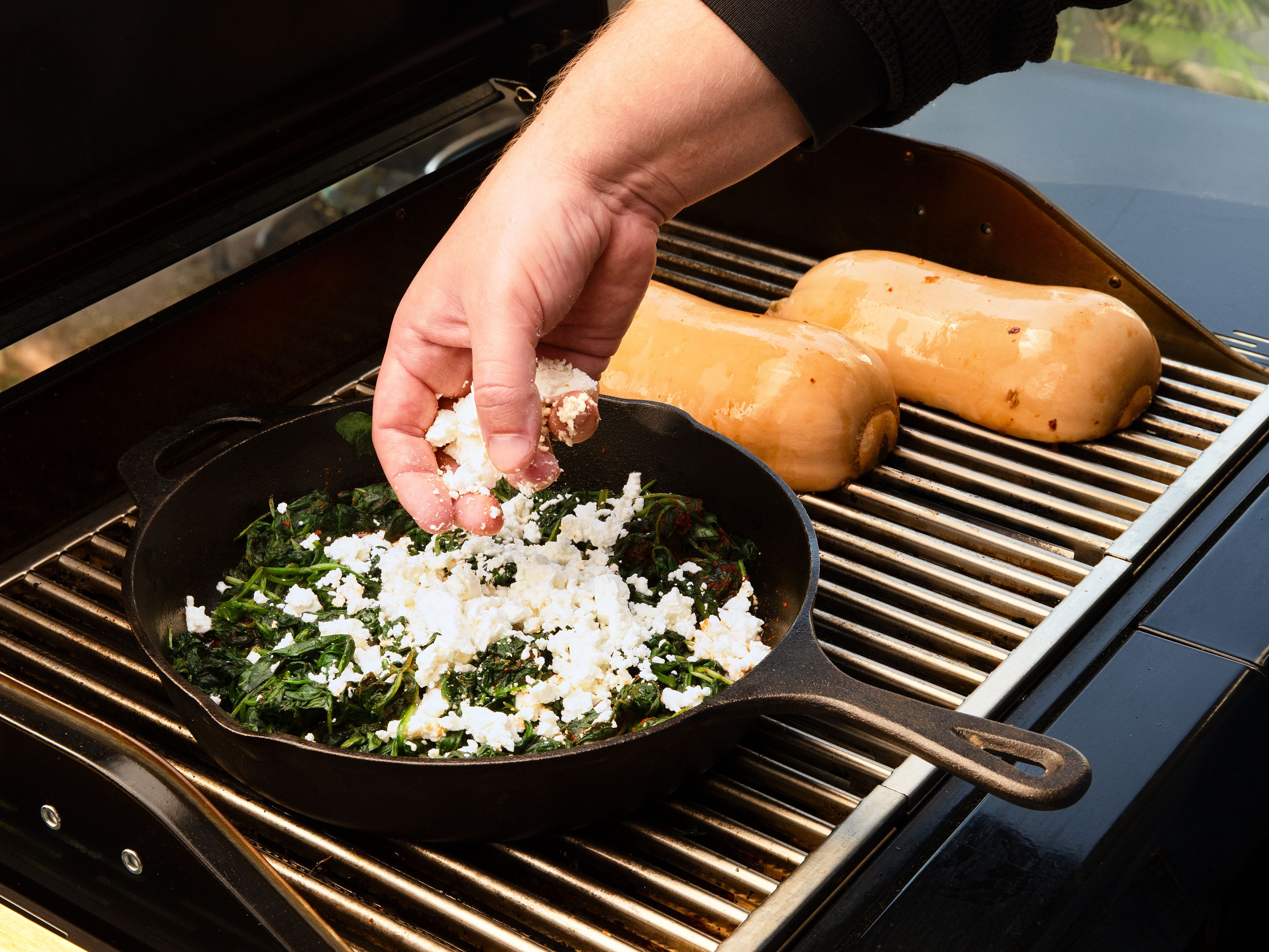 Während der Kürbis gart, eine Pfanne mit der Hälfte des restlichen Olivenöls auf dem Grill erhitzen, den Spinat darin ca. 3–5 Min. zusammenfallen lassen. Mit geräuchertem Paprikapulver, Chilipulver, Salz und Pfeffer würzen und überschüssige Flüssigkeit abgießen. Den Feta zerbröseln und unter den Spinat rühren.