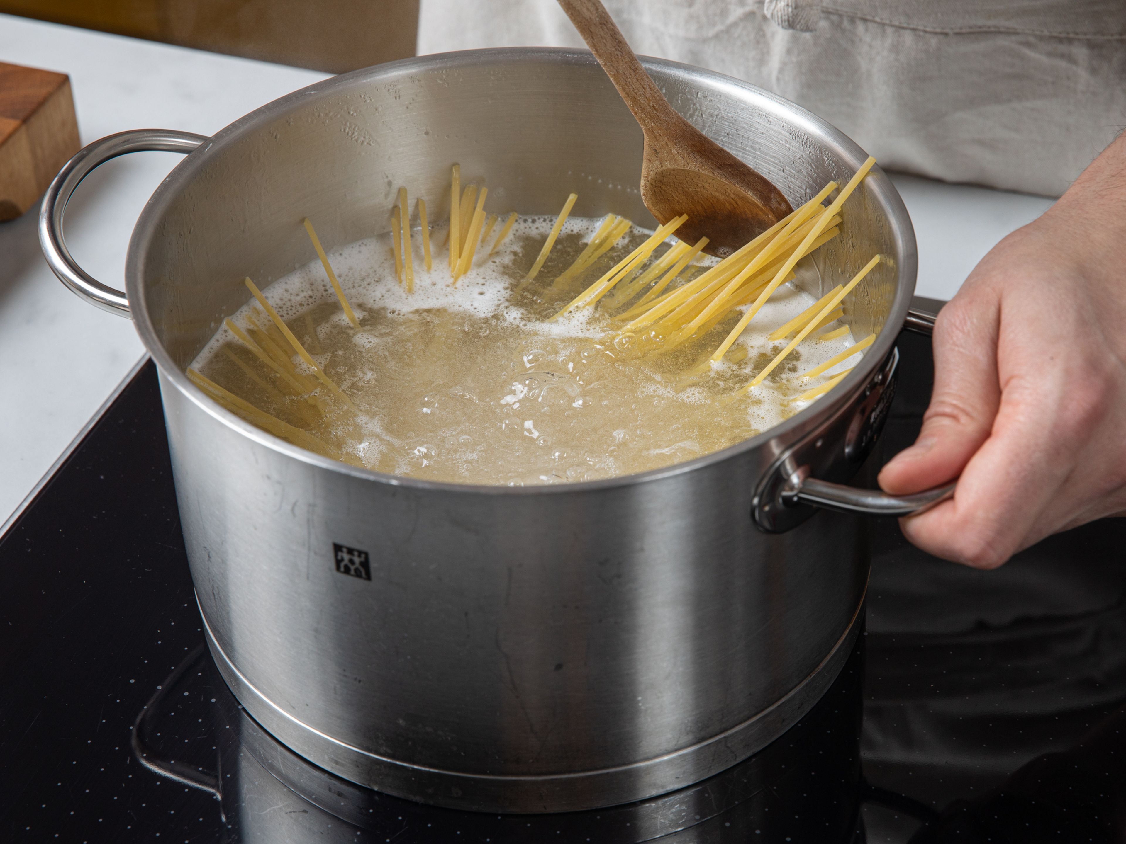 Den großen Topf aus Schritt 1 mit reichlich Wasser füllen, ausreichend Salz hinzufügen und zum Kochen bringen. Sobald das Wasser kocht, die Linguine hinzufügen und nach Packungsanweisung bissfest kochen. Einen kleinen Teil (ca. 100 ml) des Kochwassers aufheben und die Nudeln abgießen. Die Nudeln im Topf lassen.