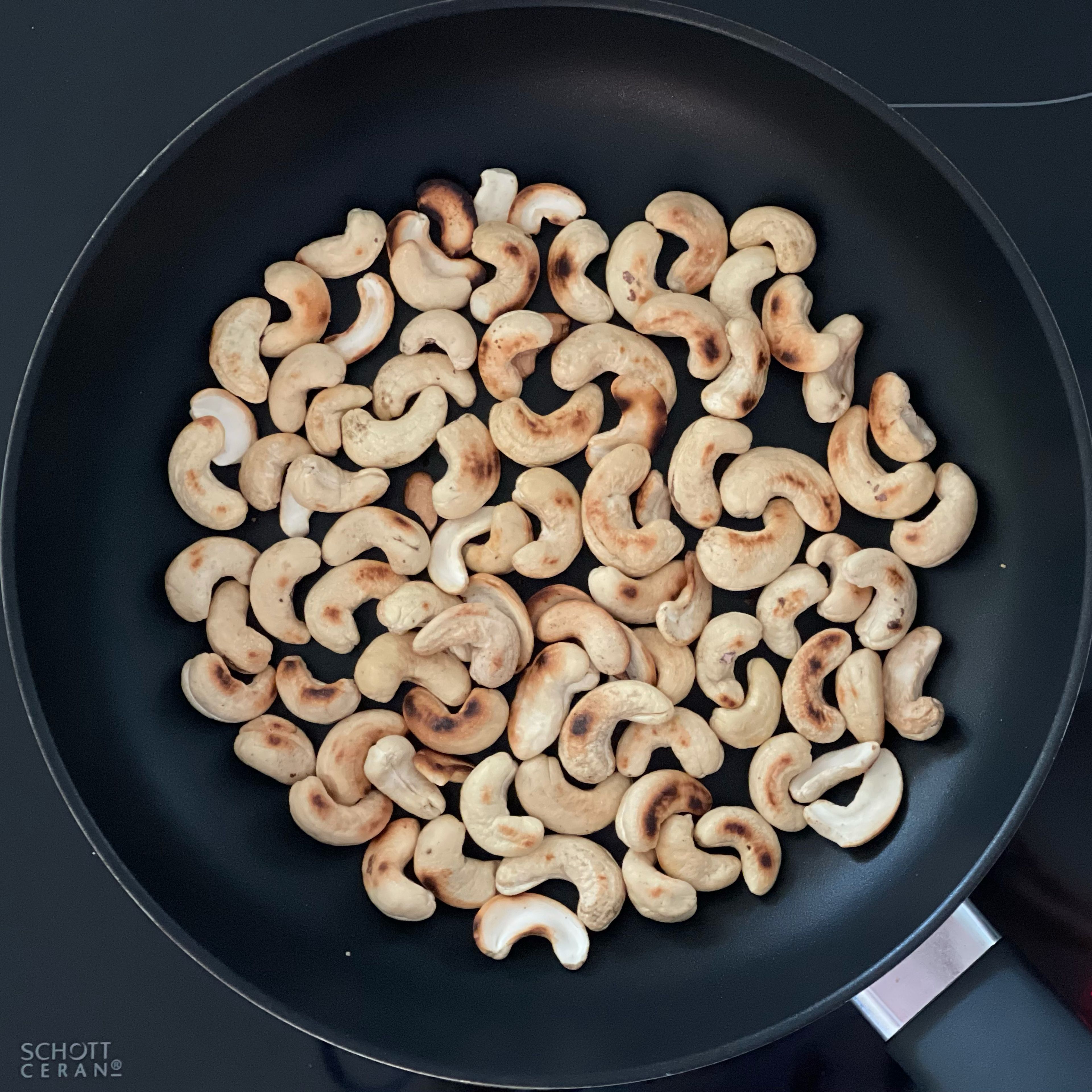 Die Cashewkerne in einer Pfanne ohne Fett anrösten bis sie leicht braun sind.