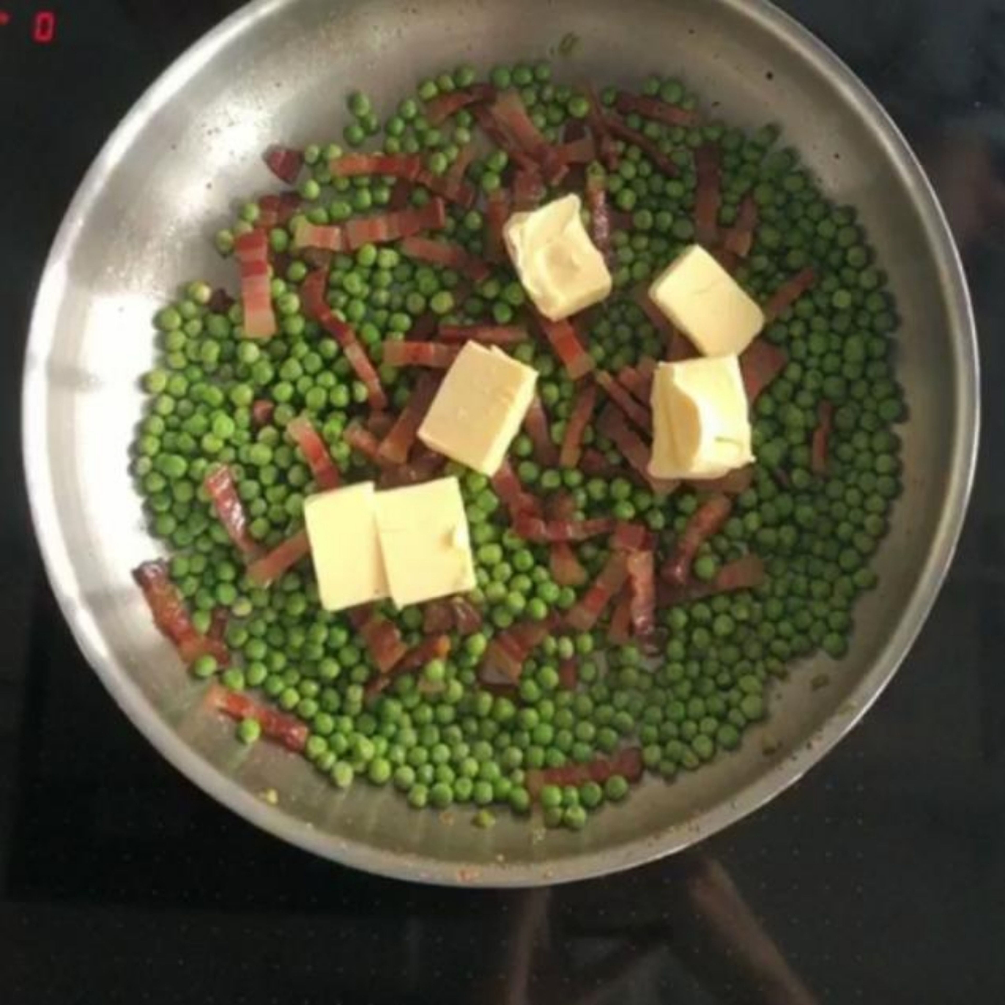 Add frozen peas to the bacon and shake the pan vigorously. After about 1 minute, stir in the cream along with the butter. Add the cooked pasta to the pan with a bit of the cooking water. Then pour in lemon juice and season with salt and pepper. Let the pasta simmer briefly and remove from heat.