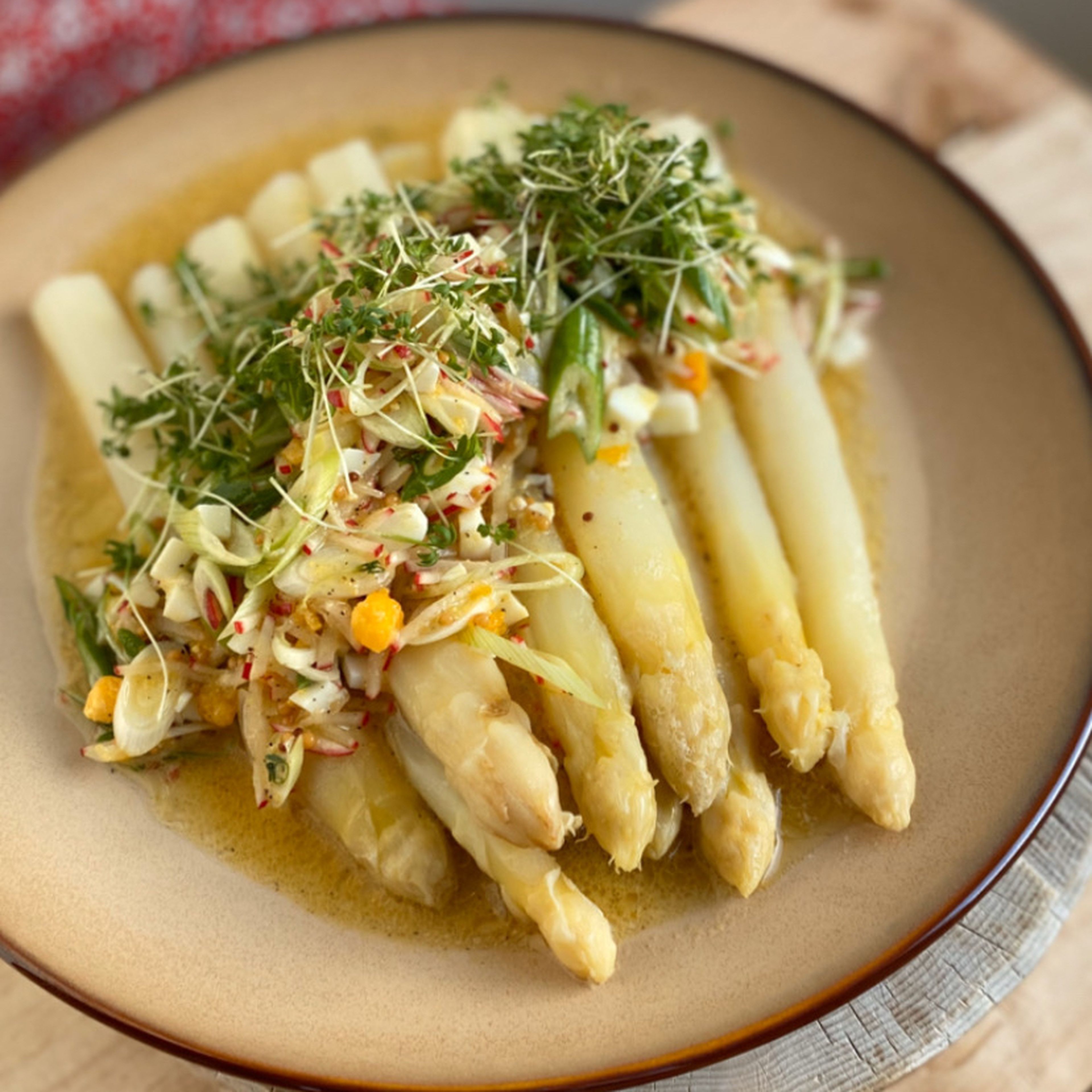 Den Spargel vorsichtig mit einer Schaumkelle aus dem Wasser heben, etwas abtropfen lassen und auf den Teller legen. Die Vinaigrette darüber verteilen und Gartenkresse darüber streuen.