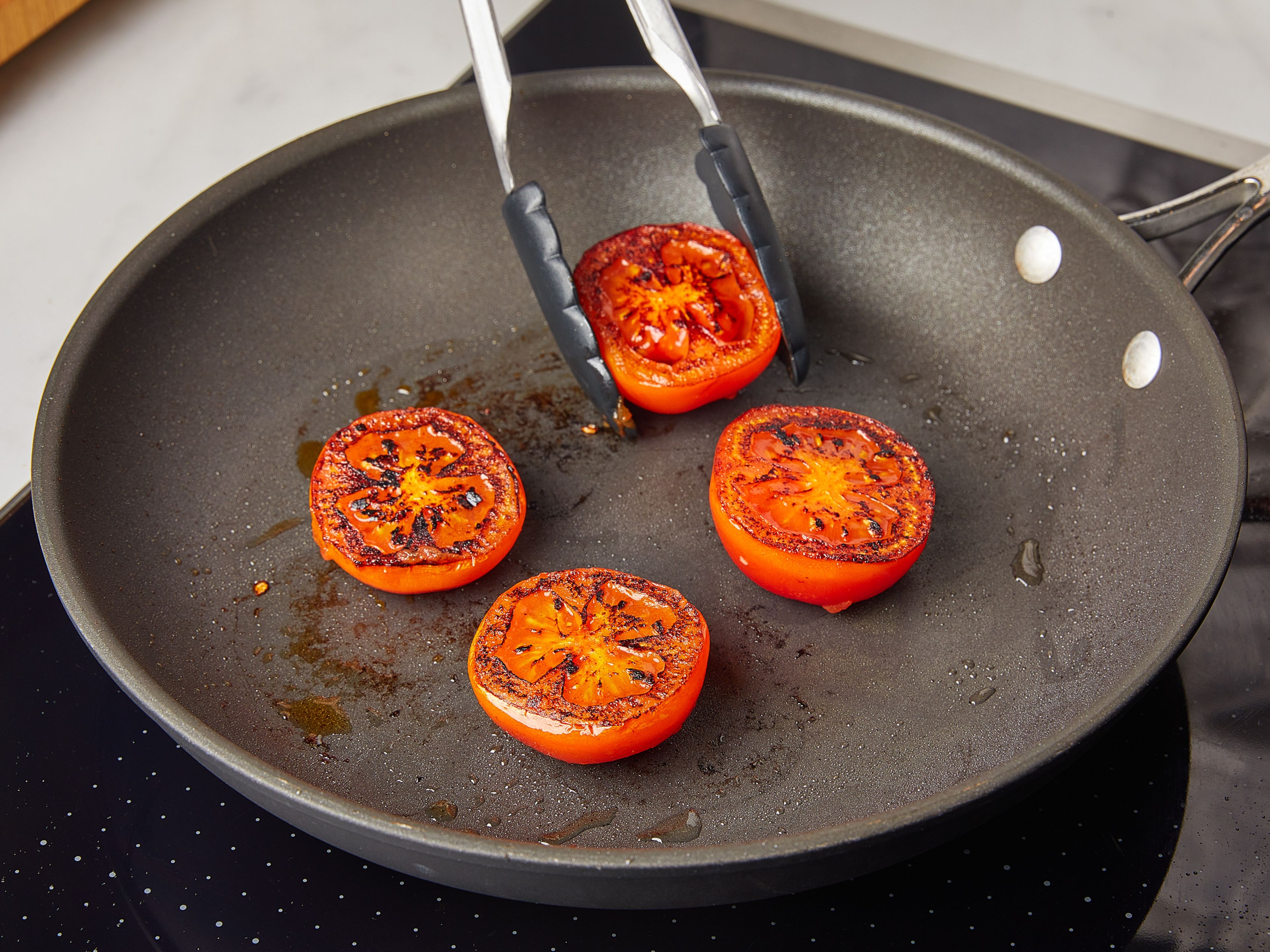 In derselben Pfanne erneut Öl erhitzen und die Tomaten ca. 3 Min. von jeder Seite braten. Die Tomatenhälften aus der Pfanne nehmen und zu den Pilzen in den Ofen geben und warm halten.