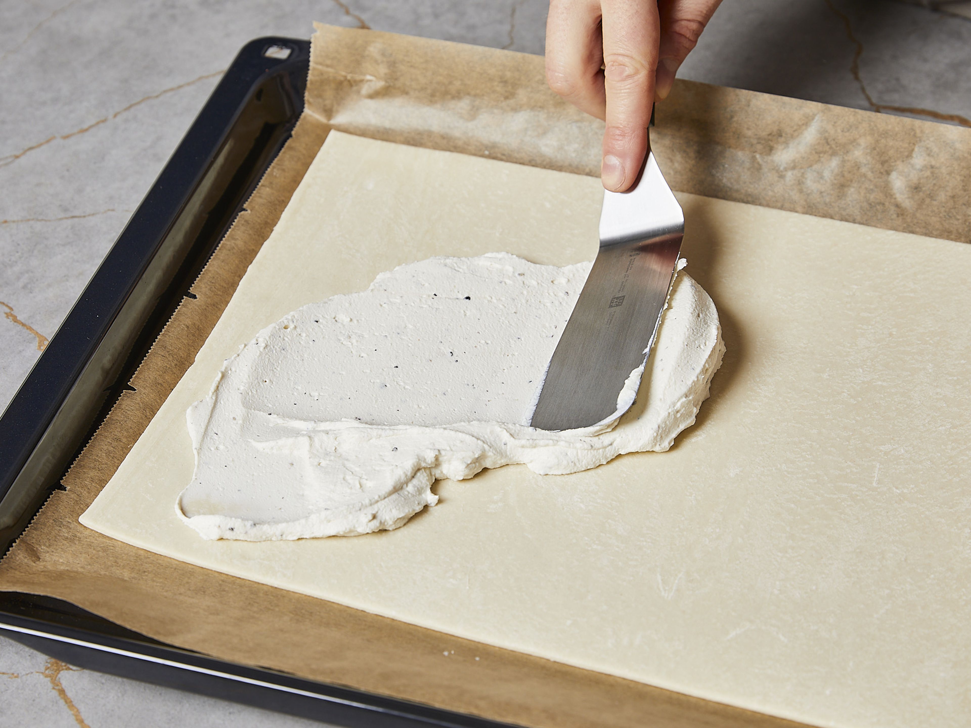 In a small bowl, mix the ricotta with the lemon zest. Season with salt and pepper to taste. Roll out the puff pastry onto a baking sheet lined with parchment paper and spread with the ricotta. Leave an approx. 1.5 cm/0.6 inch wide border free.