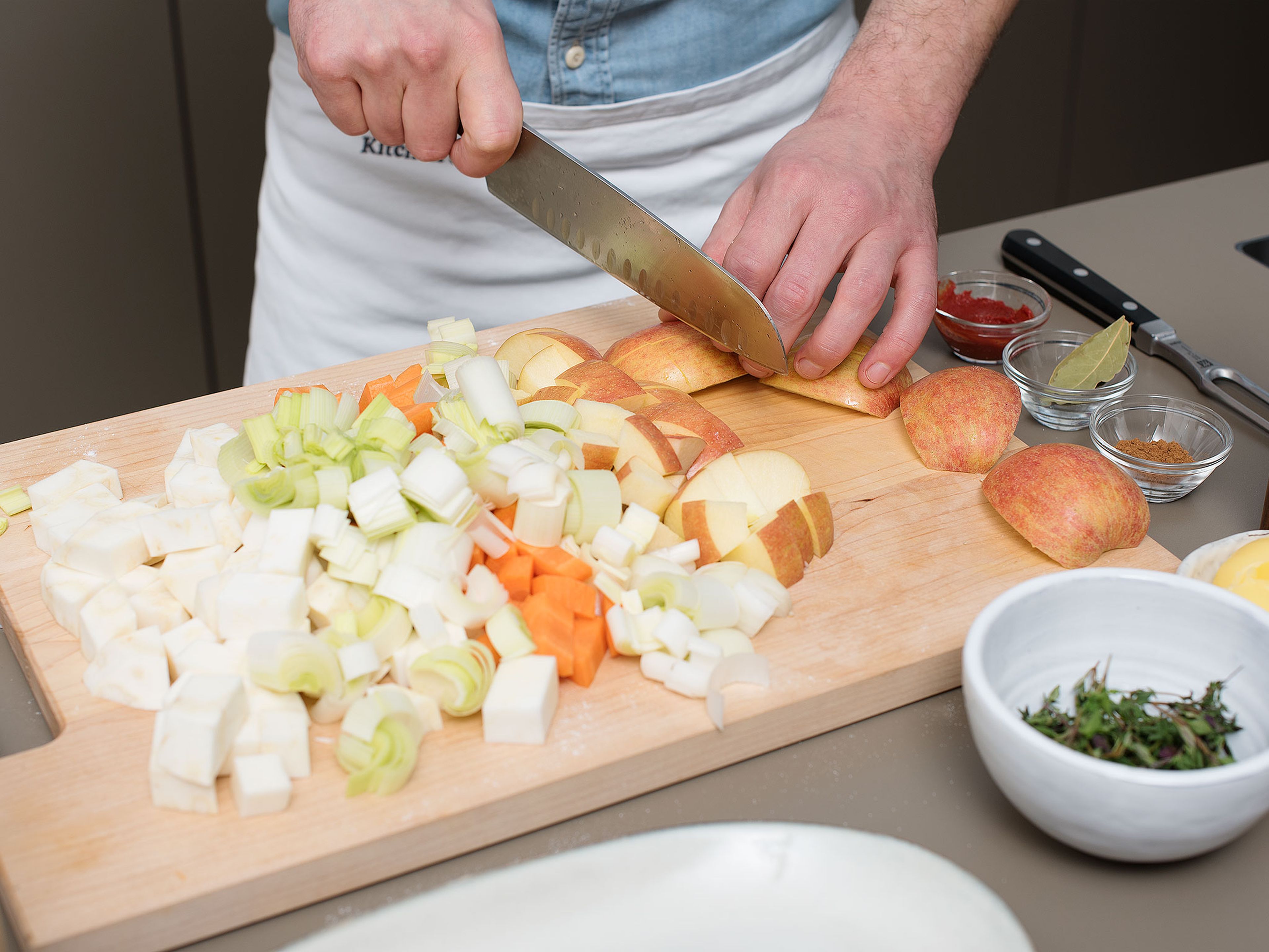Preheat oven to 120°C/250°F. Make incisions at the joint-end of the goose legs. Season with salt, then set aside. Peel and dice celery root. Peel carrots and cut into bite-sized pieces. Cut leek into 1.5-cm/ 0.5-in. slices. Peel and roughly chop onions. Cut a part of the apples into bite-sized pieces.