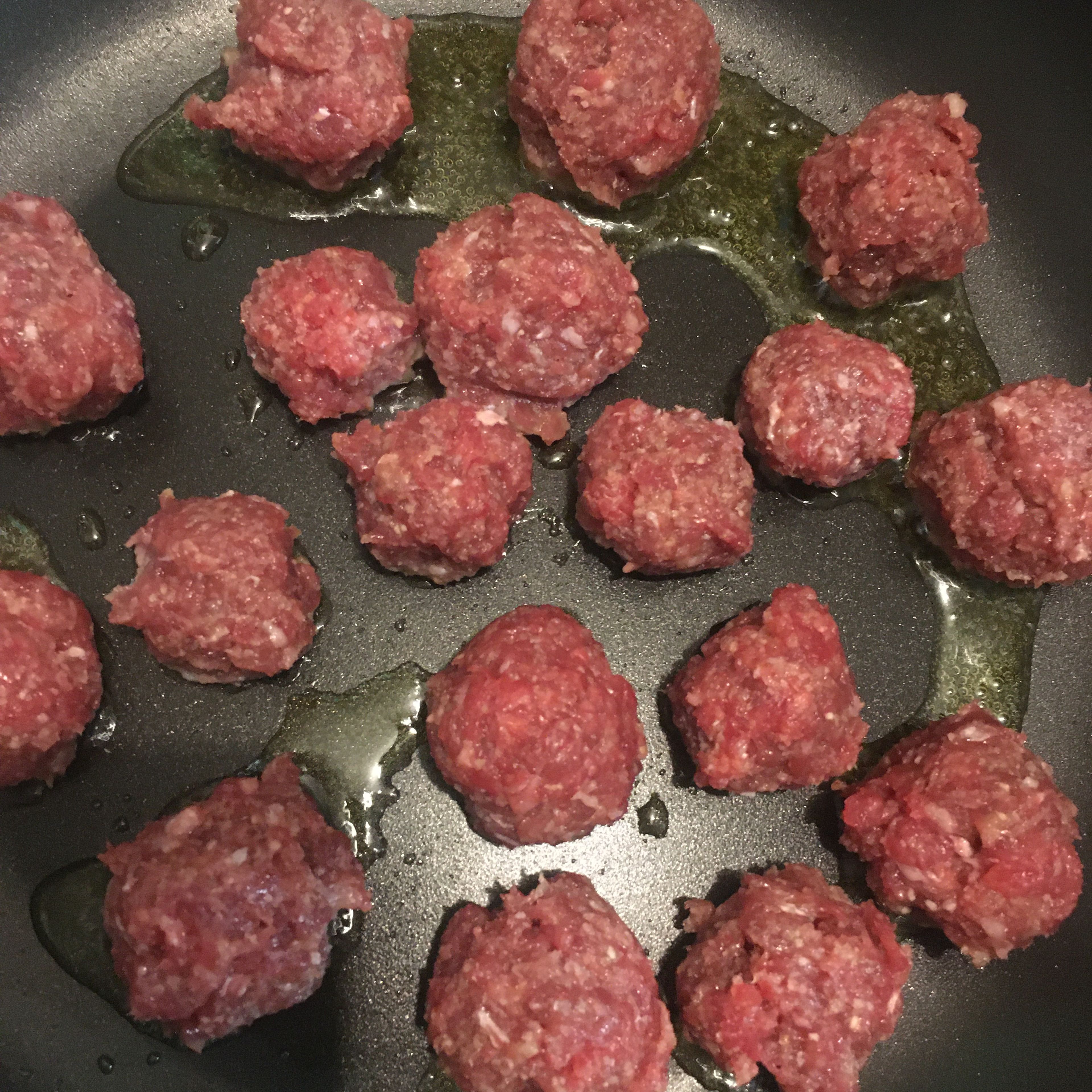 Faschierte Masse in beliebig große Kugeln formen (desto kleiner desto schneller werden sie durch) und mit etwas Olivenöl in einer beschichteten Pfanne von allen Seiten anbraten damit sie von allen Seiten angebraten aussehen. (Tipp: die Bällchen müssen noch nicht zu 100% durch sein, da sie danach noch in der Tomatensauce kochen können. :)) Wenn sie durch aussehen aus der Pfanne nehmen und beiseitestellen.