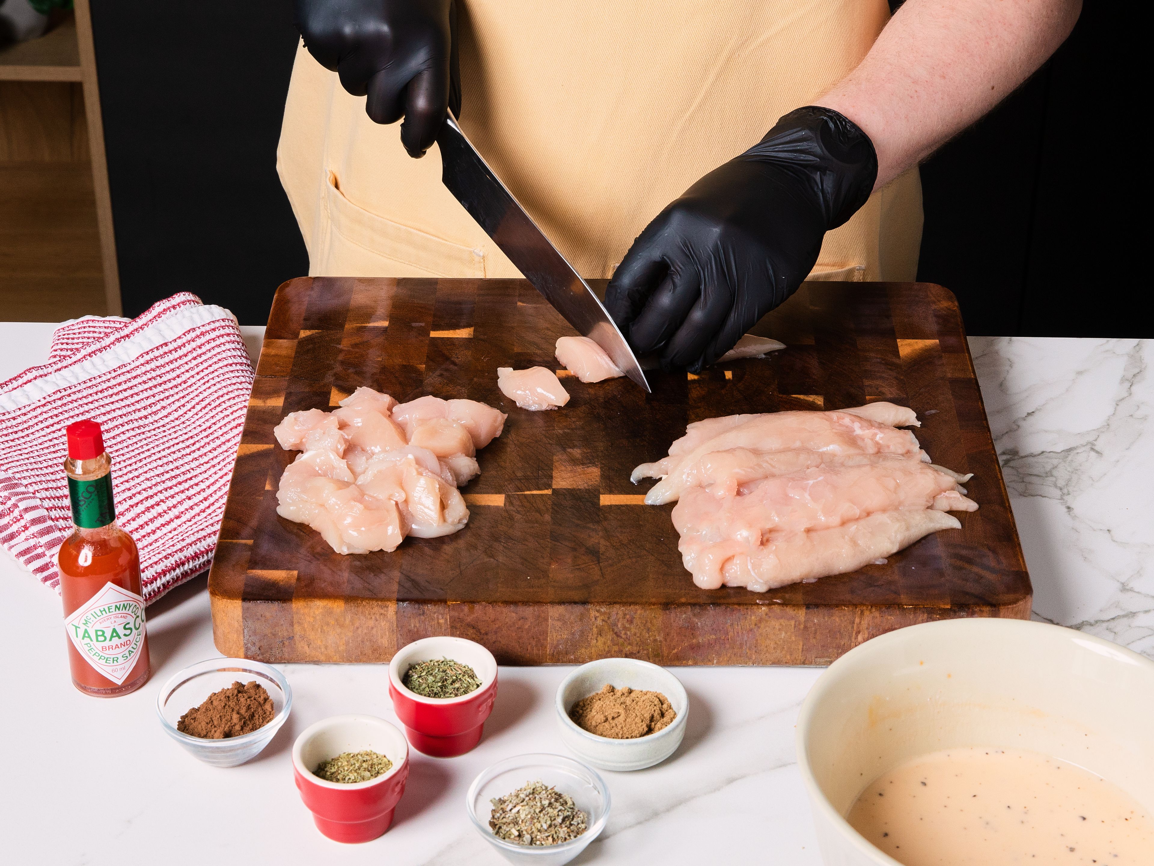 Für die Marinade Buttermilch, Ei, Tabasco, die Hälfte des Salzes und etwas schwarzen Pfeffer in einer mittelgroßen Schüssel verquirlen. Hähnchenfilets in ca. 2 cm große Stücke schneiden, zur Marinade geben und vermischen, bis sie vollständig damit bedeckt sind. Für ca. 30 Min. oder bis zu 12 Std. marinieren lassen.