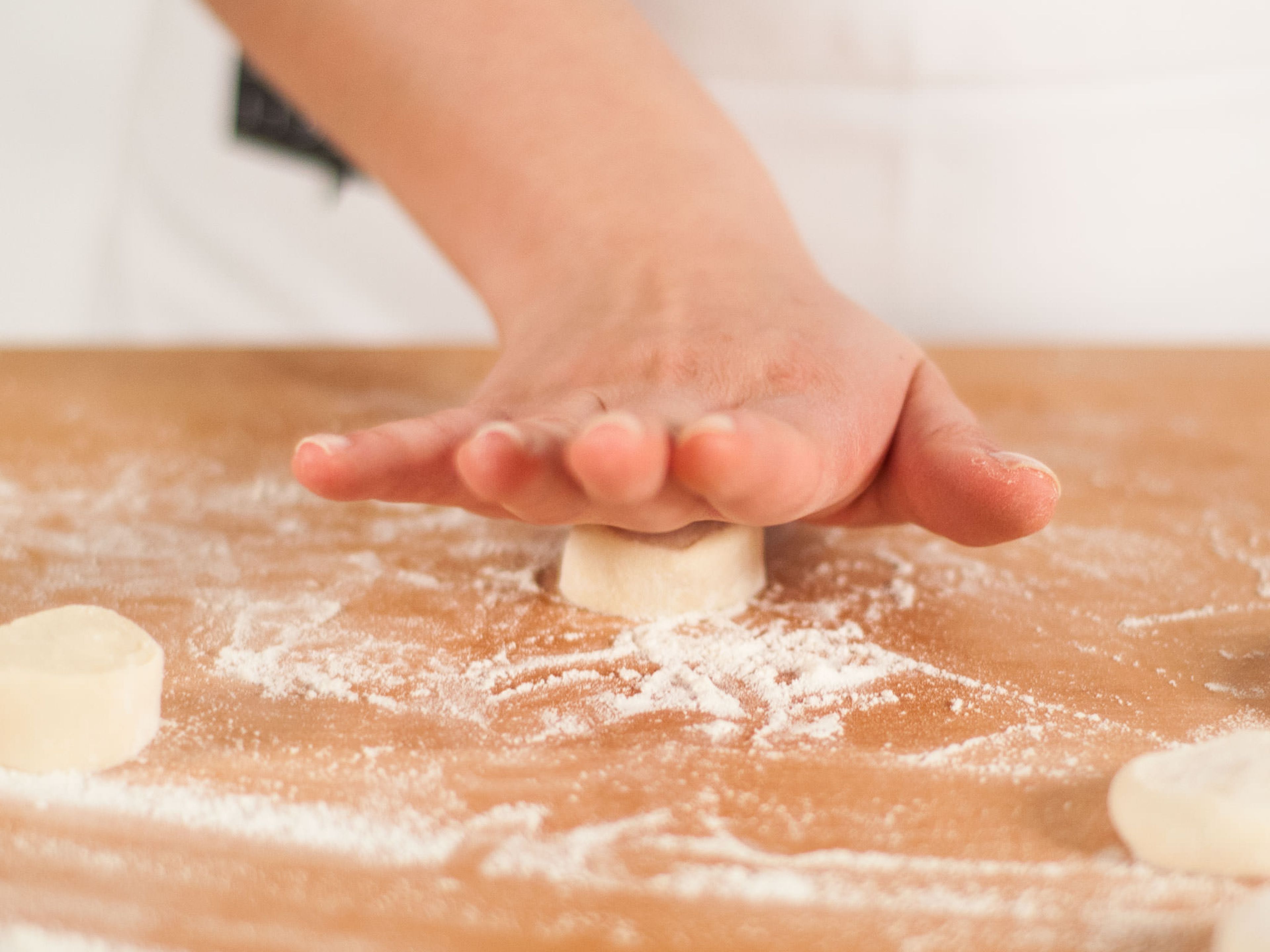 Roll dough portions on a lightly floured surface to cover each side with flour. Then, using little pressure, flatten the dough pieces with the palm of your hand.