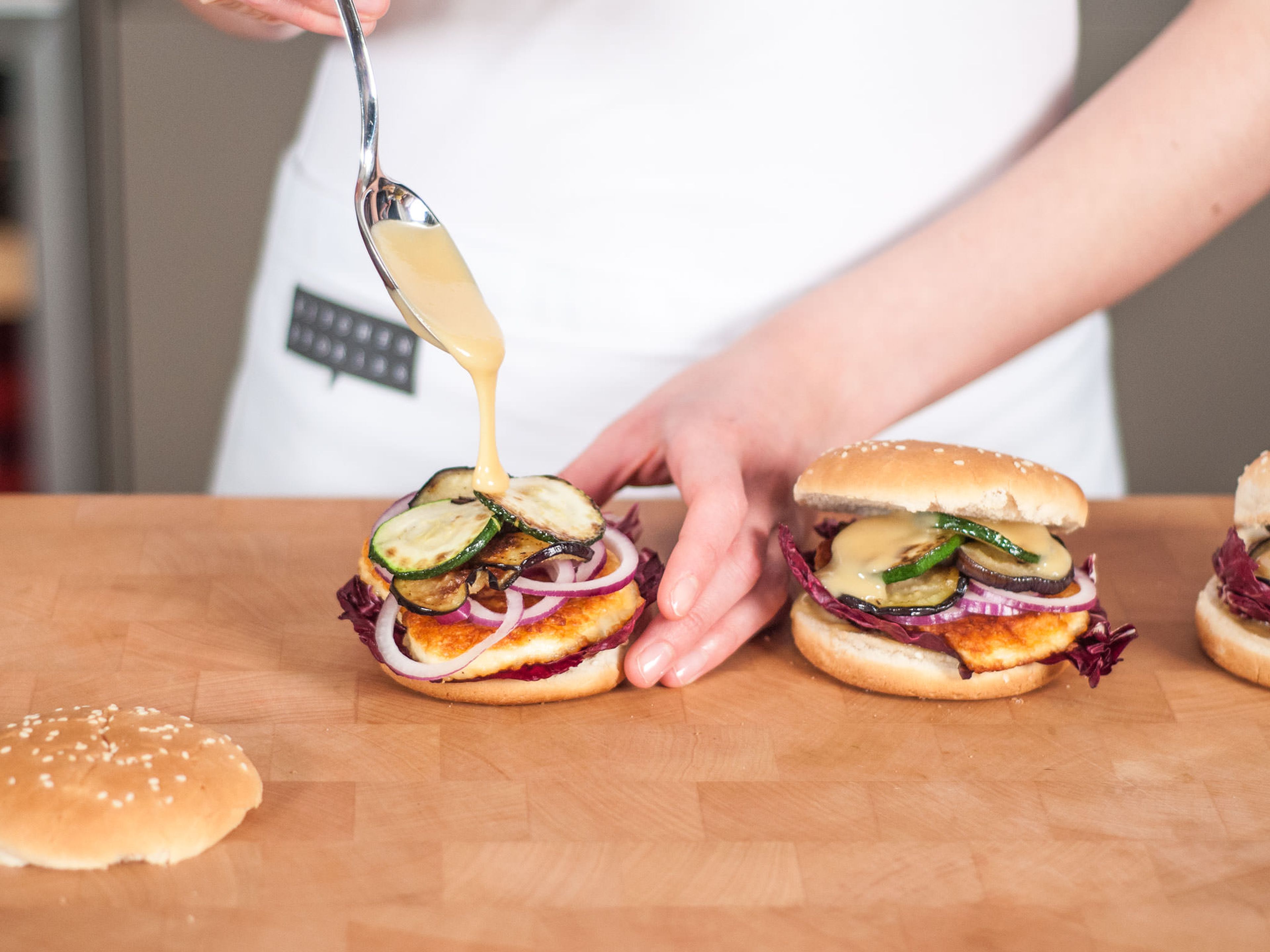 Brush each burger bun with honey mustard sauce. Place radicchio on the bottom part and layer cheese, zucchini, eggplant, and onion rings on top. Pick mint leaves and place on top of vegetables. Drizzle with more sauce, cover with the upper part of the bun, and enjoy with homemade french fries!