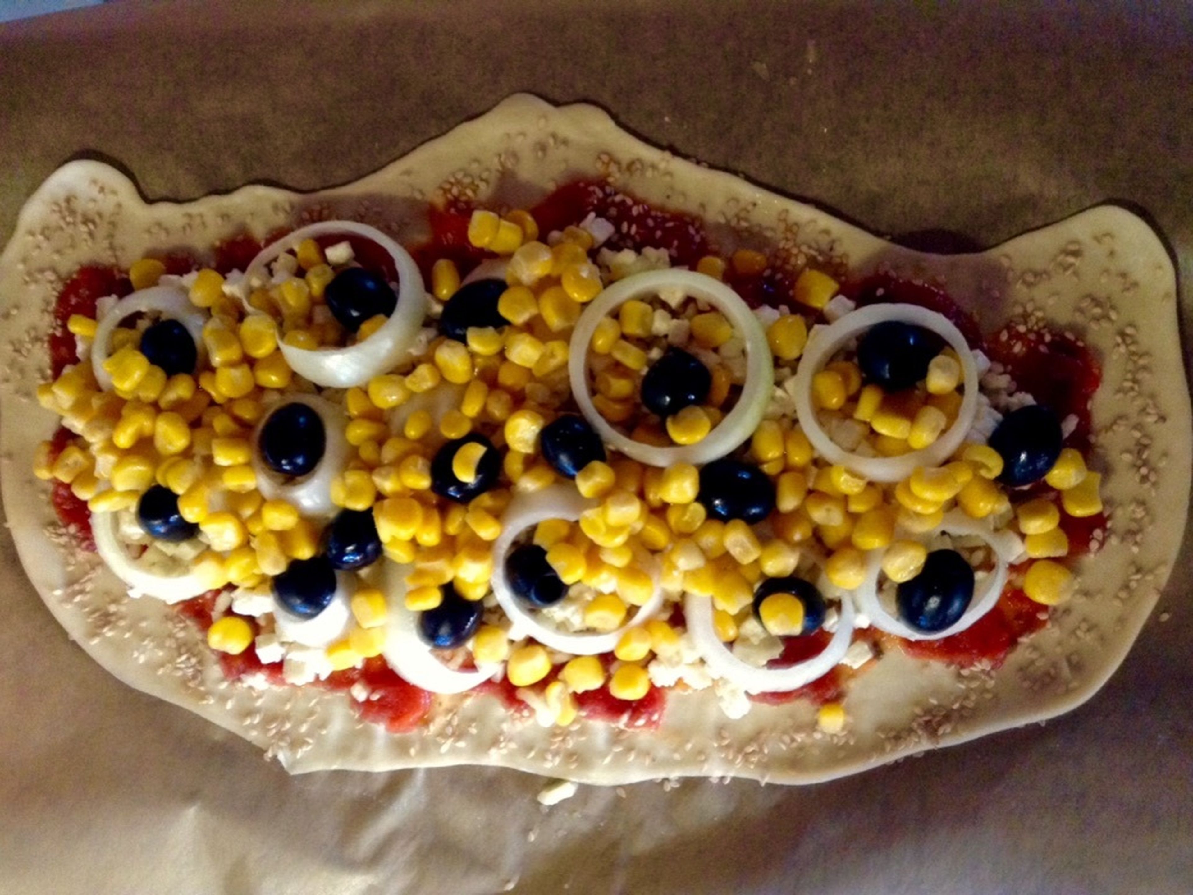 Next, add the toppings. Either put everything on top randomly, or decorate your pizza creatively, as you know—you eat with your eyes first! I started with the sweetcorn (well drained in advance), followed by onion rings (cut beforehand), and finished off with olives in the gaps (well drained).