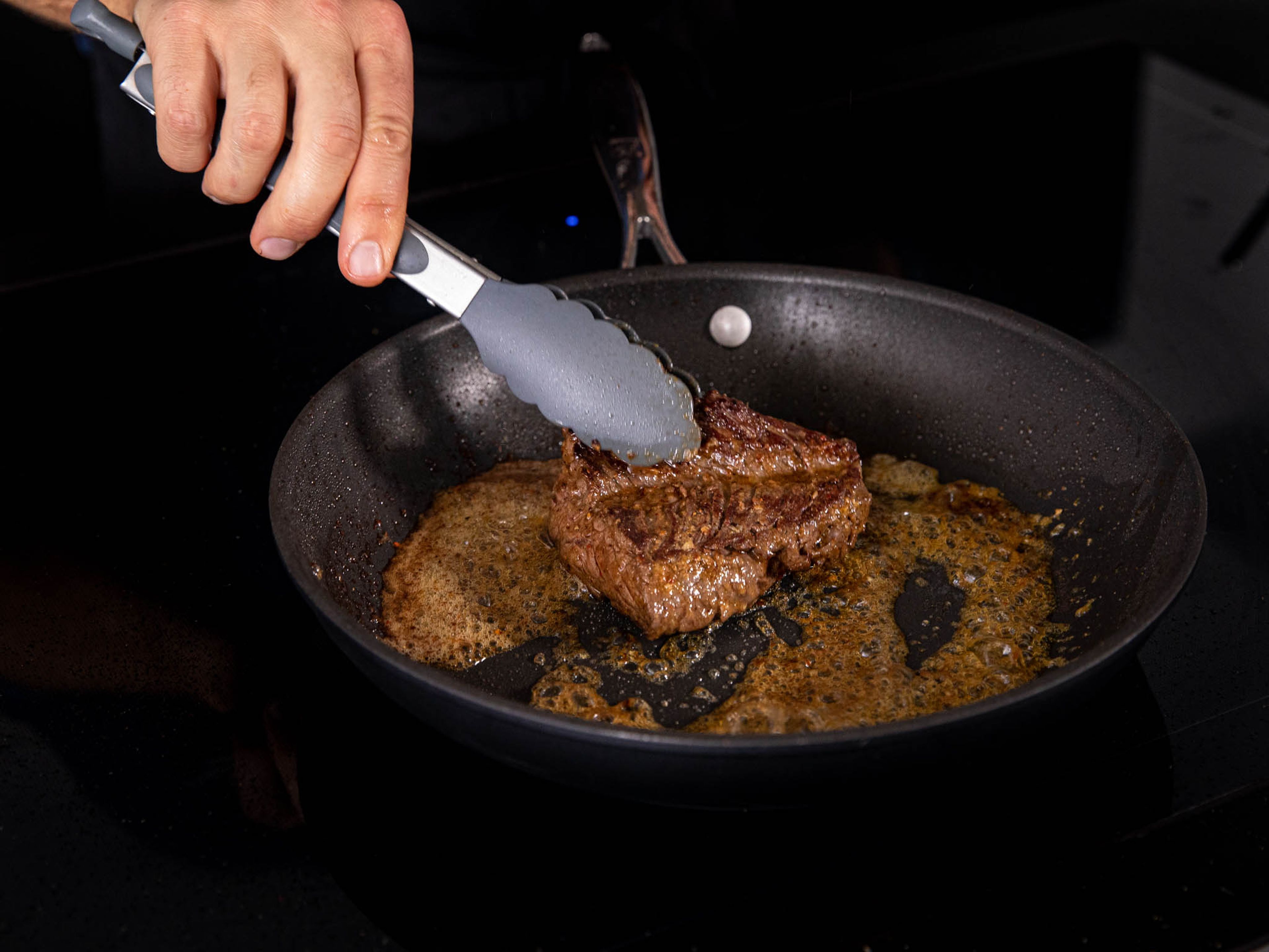 Stelle eine beschichtete Bratpfanne auf mittlere bis hohe Hitze. Das Öl hinzufügen und für 1 – 2 Minuten erhitzen. Jetzt das Steak mit Salz würzen. Sobald die Pfanne sehr heiß ist, das Steak hineinlegen und für 1 Minute unangetastet scharf anbraten. Das Steak wenden und für 1 Minute weiter braten. Jetzt etwa ein weiteres Drittel der restlichen Butter hinzugeben und das Steak 45 Sekunden auf jeder Seite fertig braten. Wenn du ein Küchenthermometer hast, überprüfe, ob die Mitte des Steaks etwa 53°C hat. Das bedeutet, dass das Steak, nach dem Ruhen, Medium rare ist. Perfekt für diese Art von Steak. Nehme das Steak heraus und lasse es 4 Minuten auf einer warmen Platte oder einem Teller ruhen.