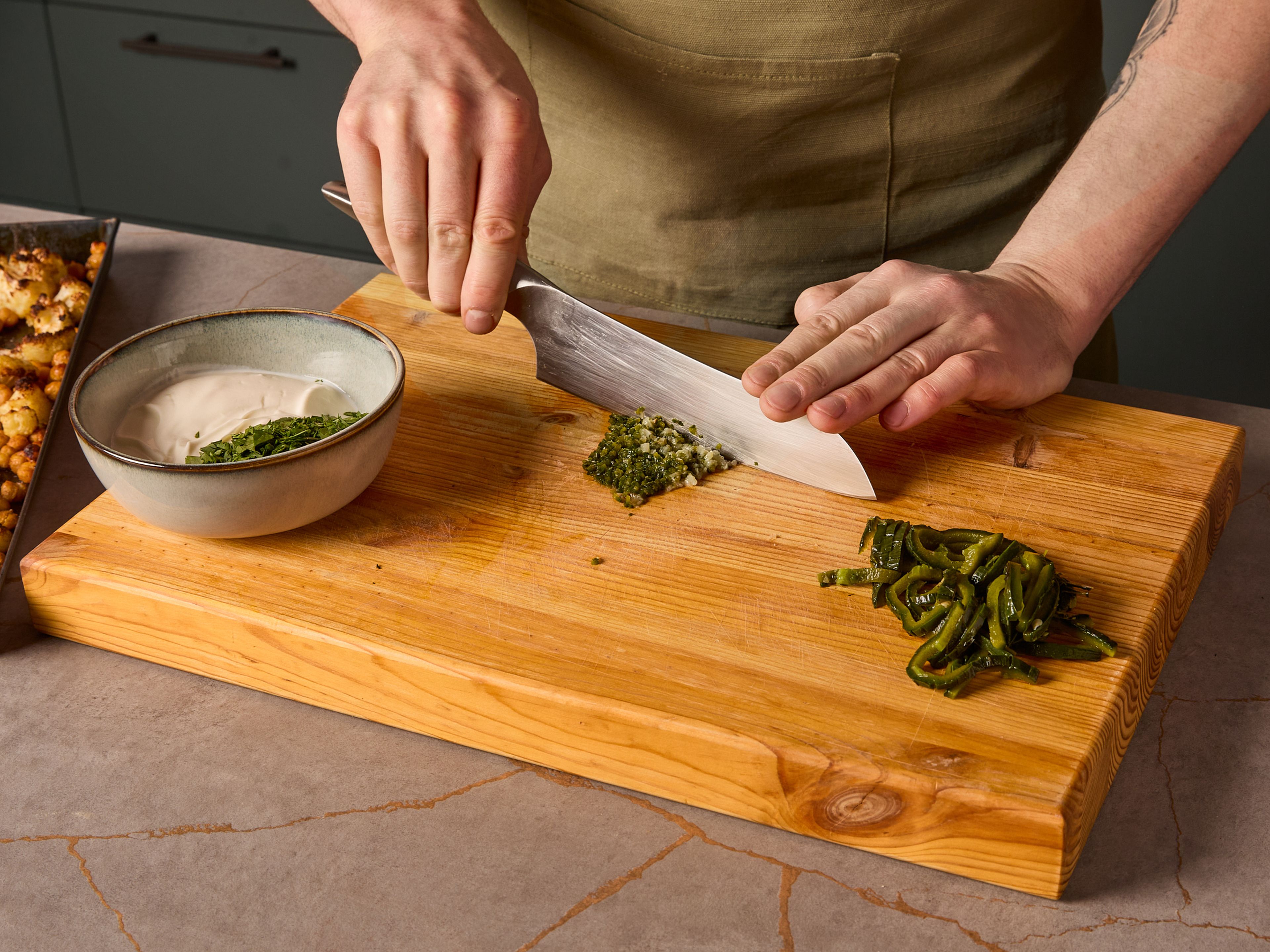 Knoblauch schälen. Jalapeños schälen und entkernen. Zwei der Jalapeños in Streifen schneiden und beiseitelegen. Die übrige Jalapeño zusammen mit dem Knoblauch fein hacken, bis eine stückige Paste entsteht. Koriander fein hacken. Joghurt in eine Schüssel geben, die Jalapeño-Knoblauch-Mischung und den Koriander hinzufügen. Verrühren und mit Salz abschmecken. Bis zum Servieren kalt stellen.