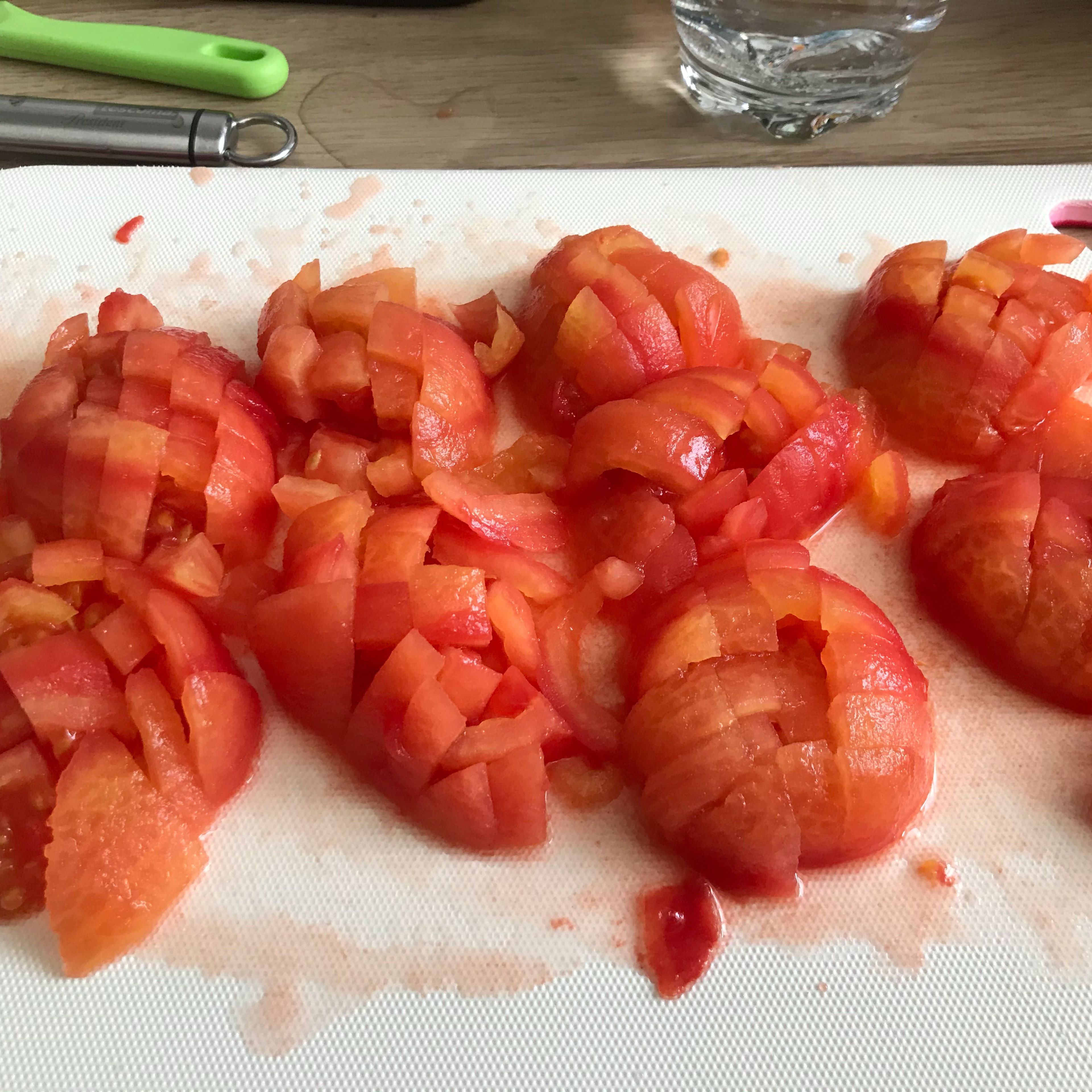 Tomatenmark und die Gewürze hinzufügen. Die Tomaten enthäuten und würfeln. Zu dem Gemüse geben und die Temperatur auf 140 °C erhöhen. Das Mehl einwiegen und bei geschlossenem Deckel mit eingesetztem Messbecher weiter köcheln lassen (3D-Rührer | Stufe 1| 98°C | 6 Min.).