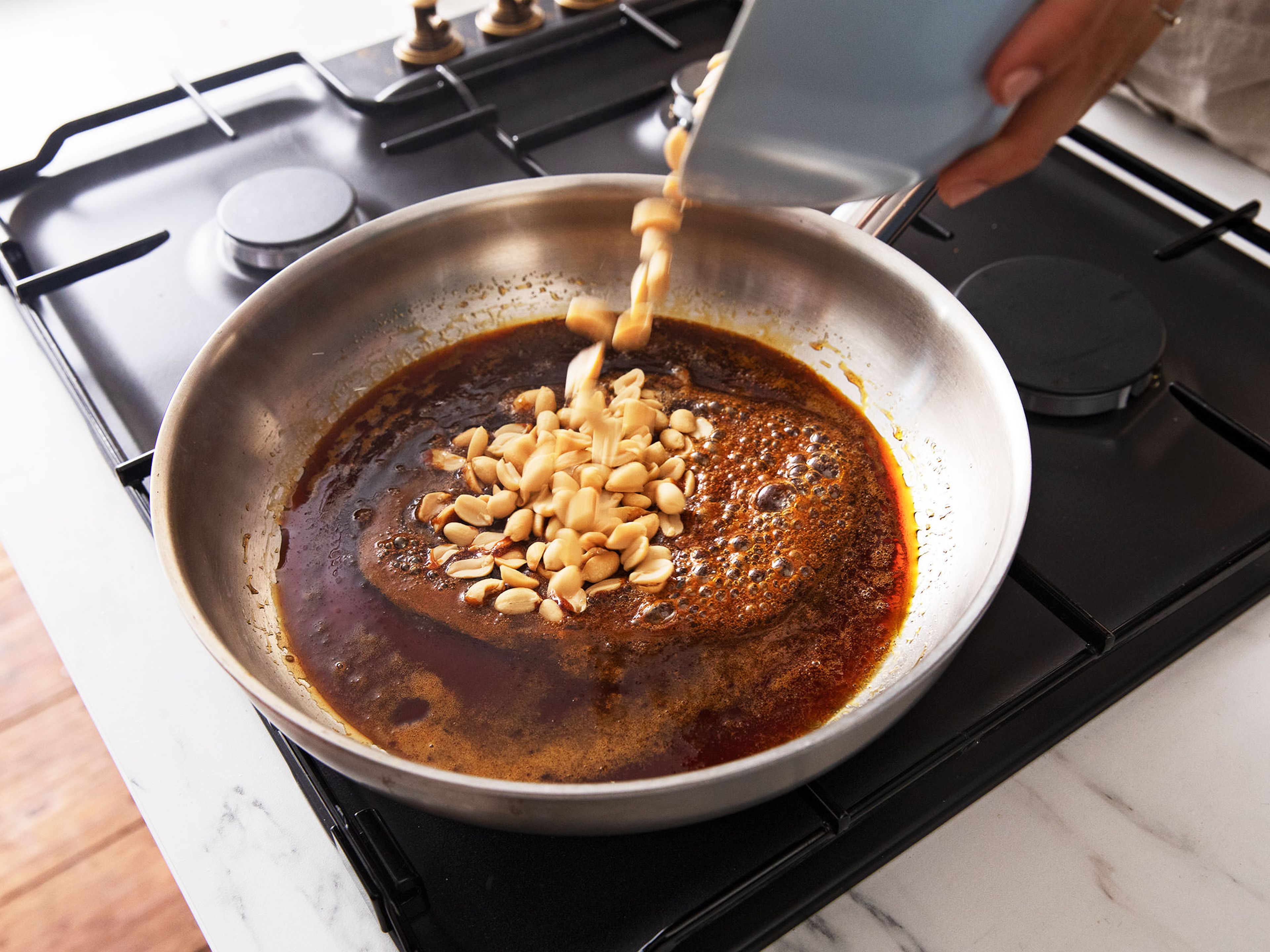 Put the sugar in a pan and caramelize over medium heat, do not stir but instead tilt the pan to melt it evenly. When the sugar is completely dissolved and amber in color, add the butter, peanuts, and salt and stir to combine.
