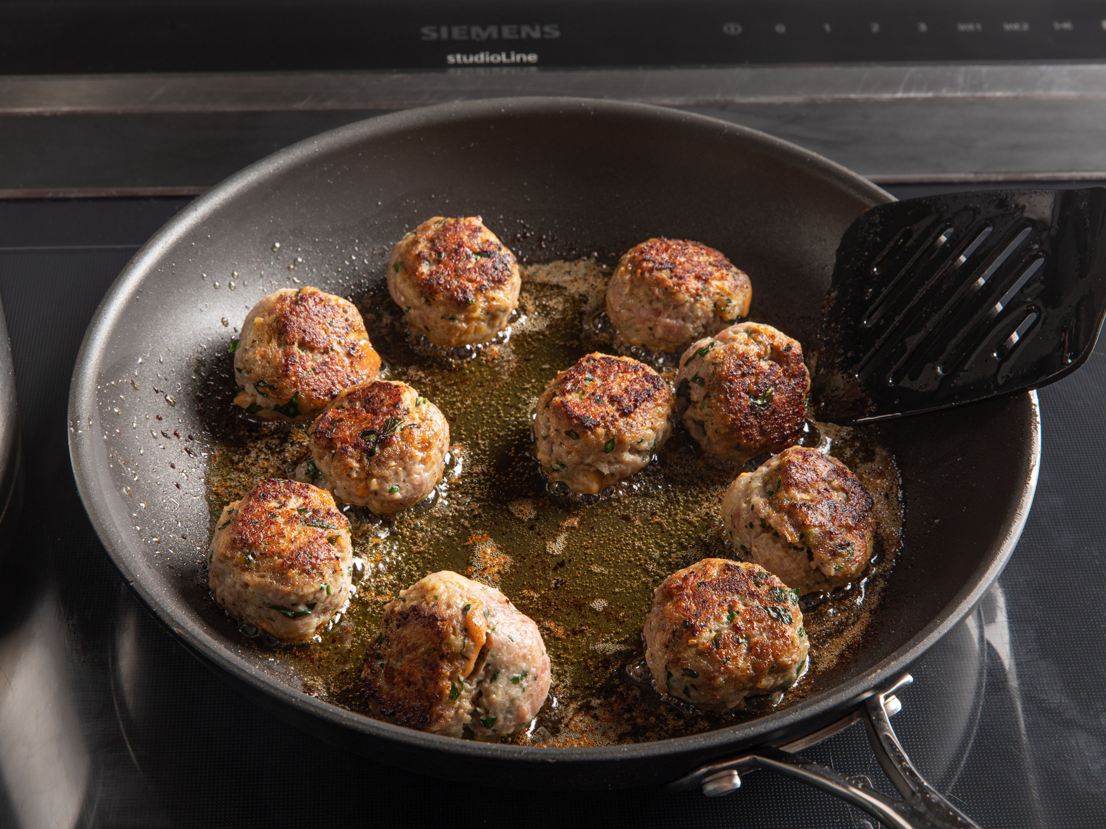 Heat a large frying pan on medium heat and add the rest of the olive oil. Add half of the meatballs and fry for approx. 10 min., gently flipping with a spatula halfway through. Don’t overcrowd the pan to ensure they get a golden brown exterior. Once cooked, remove and place them in a bowl, along with any brown bits on the bottom of the pan. Repeat in batches, as needed, until used up.