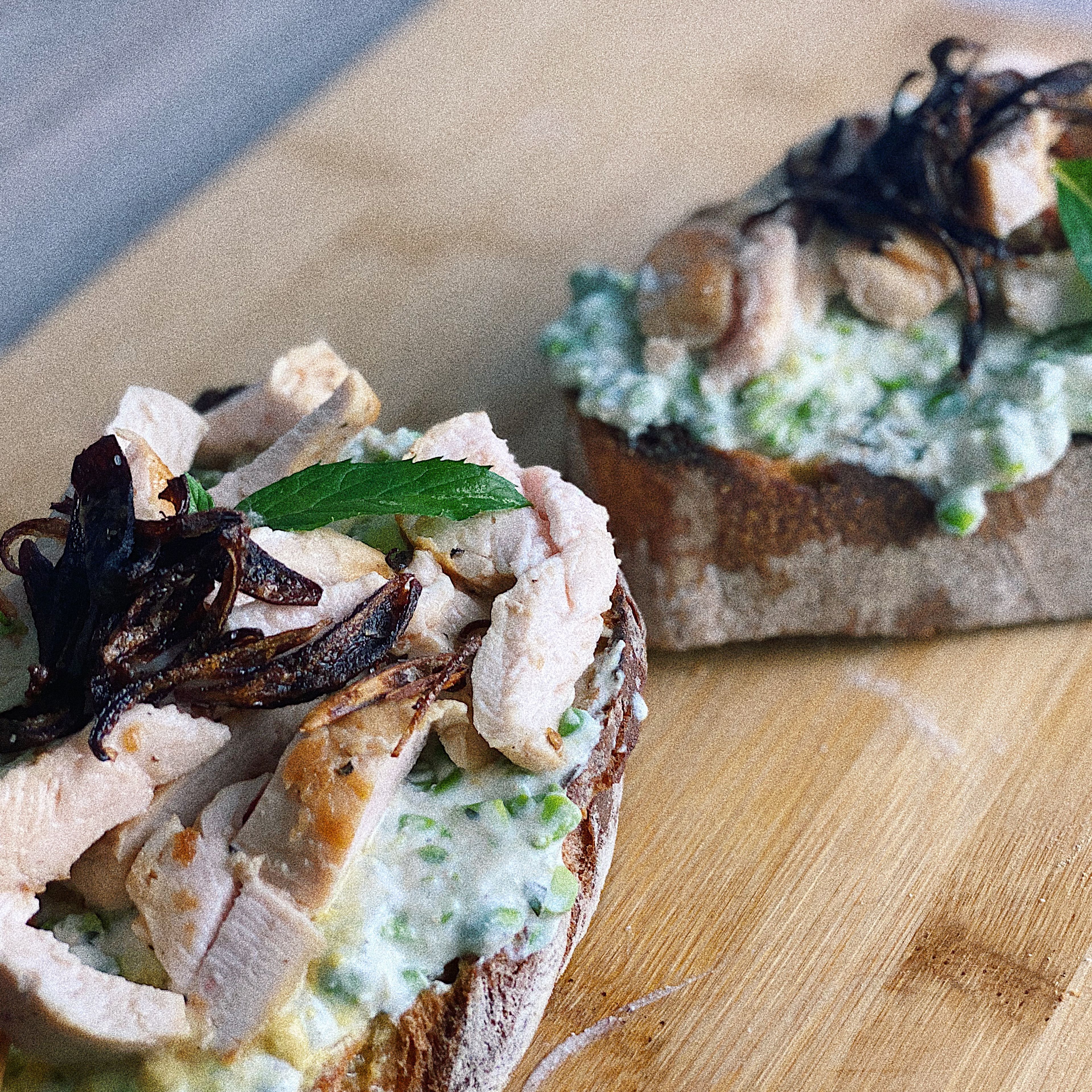 TO SERVE. Divide the mashed peas between the 2 grilled toasts, then fan half the chicken on top of each toast. Season with more salt and pepper. Drizzle with the dressing, top with crispy shallots, and garnish with mint and lemon zest.