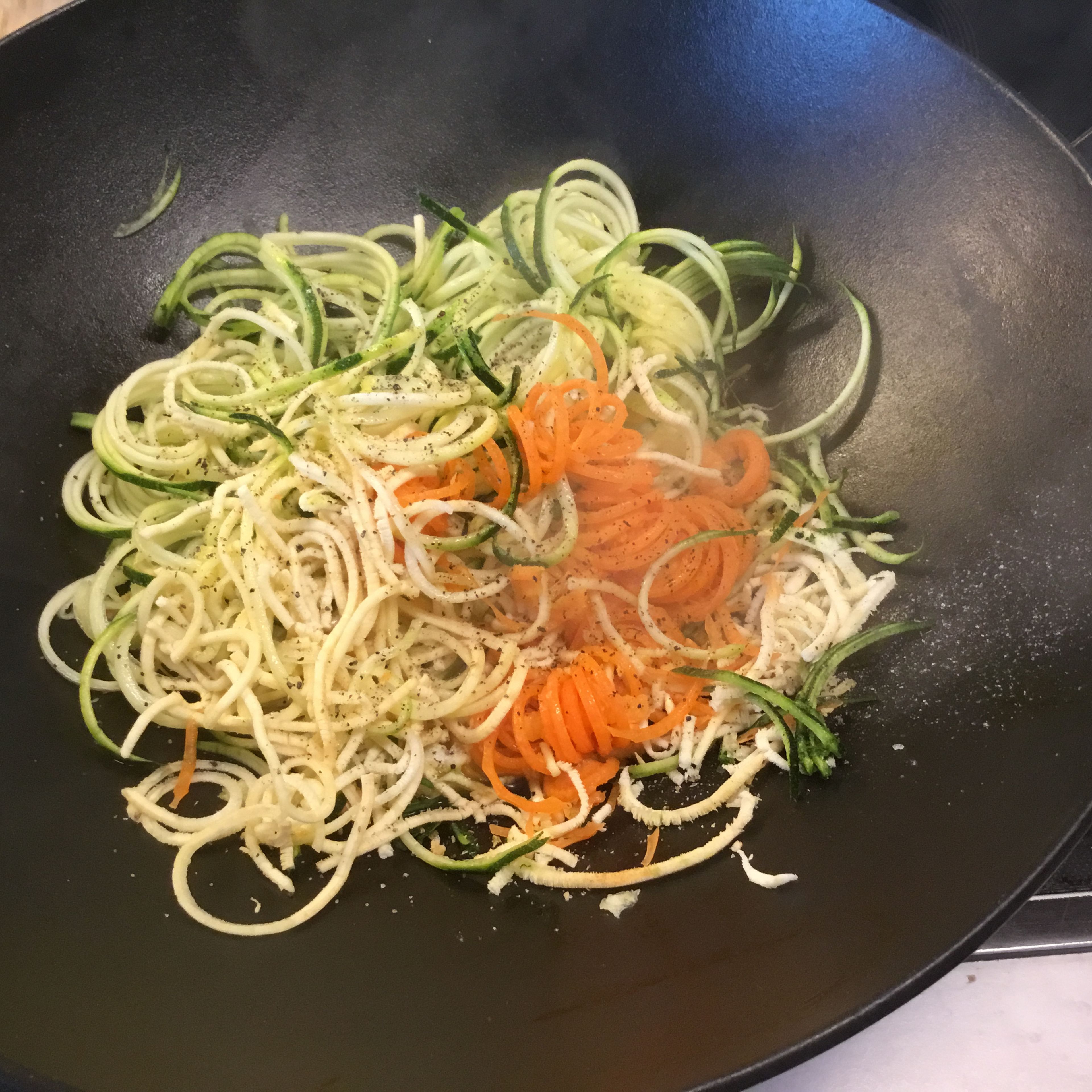 Die Wurzel/Gemüsespaghetti in wenig Rapsöl im Wok oder anderem Kochtopf kurz erhitzen, evtl 50ml Gemüsesuppe dazufügen wenn sich zu wenig Gemüsesaft entwickelt. Wenig salzen und pfeffern und wirklich nur ganz kurz erhitzen damit die Spaghetti knackig bleiben...max 3 Minuten.