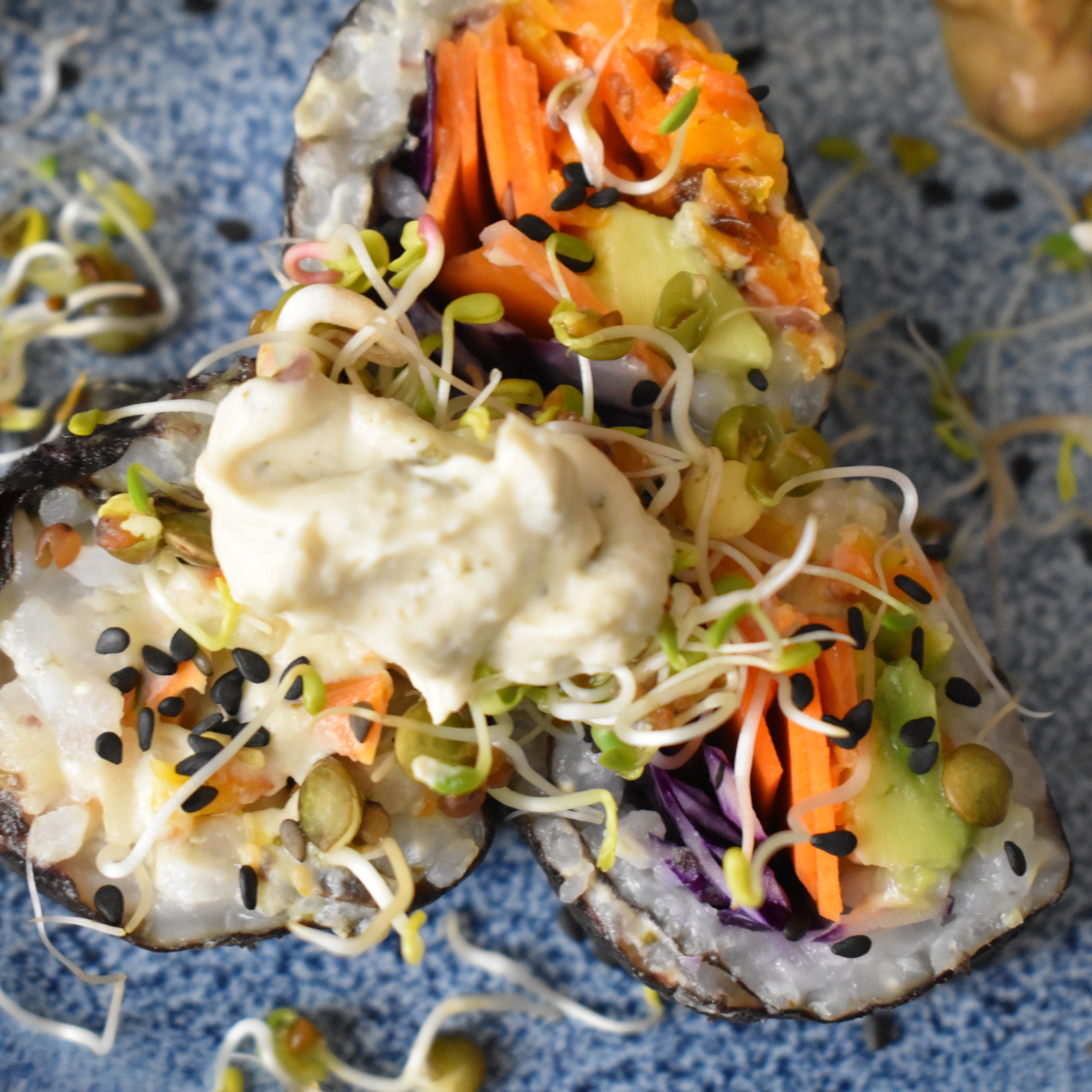 Sushi in Stücke schneiden und mit Sesam und Sprossen garnieren… Mit Sojasauce und Erdnussauce servieren.💚
