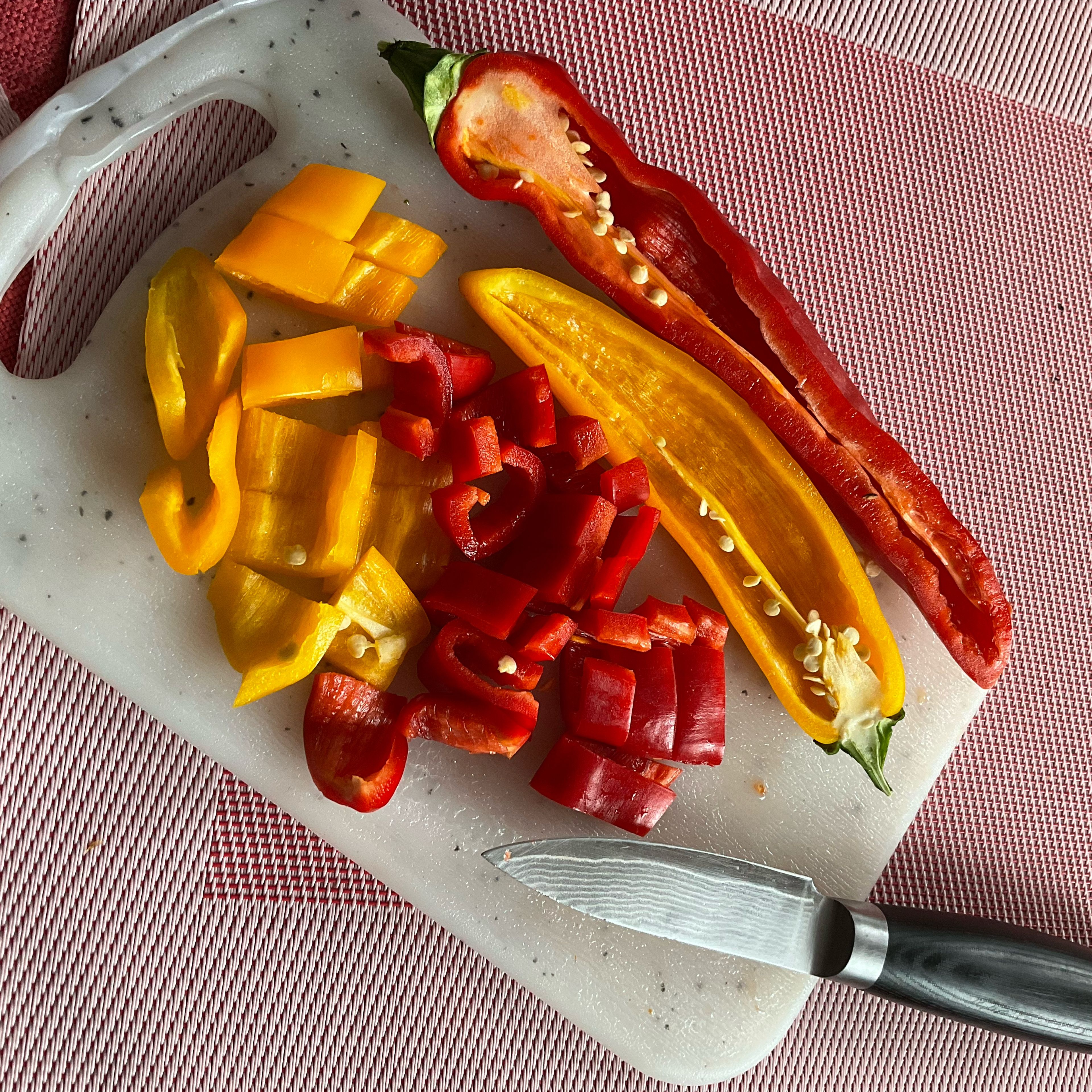 Je ein halbe Spitzpaprika in rot und gelb (andere normale Paprika geht auch) halbieren, entkernen und in grobe Paprikaschnitzer schneiden.