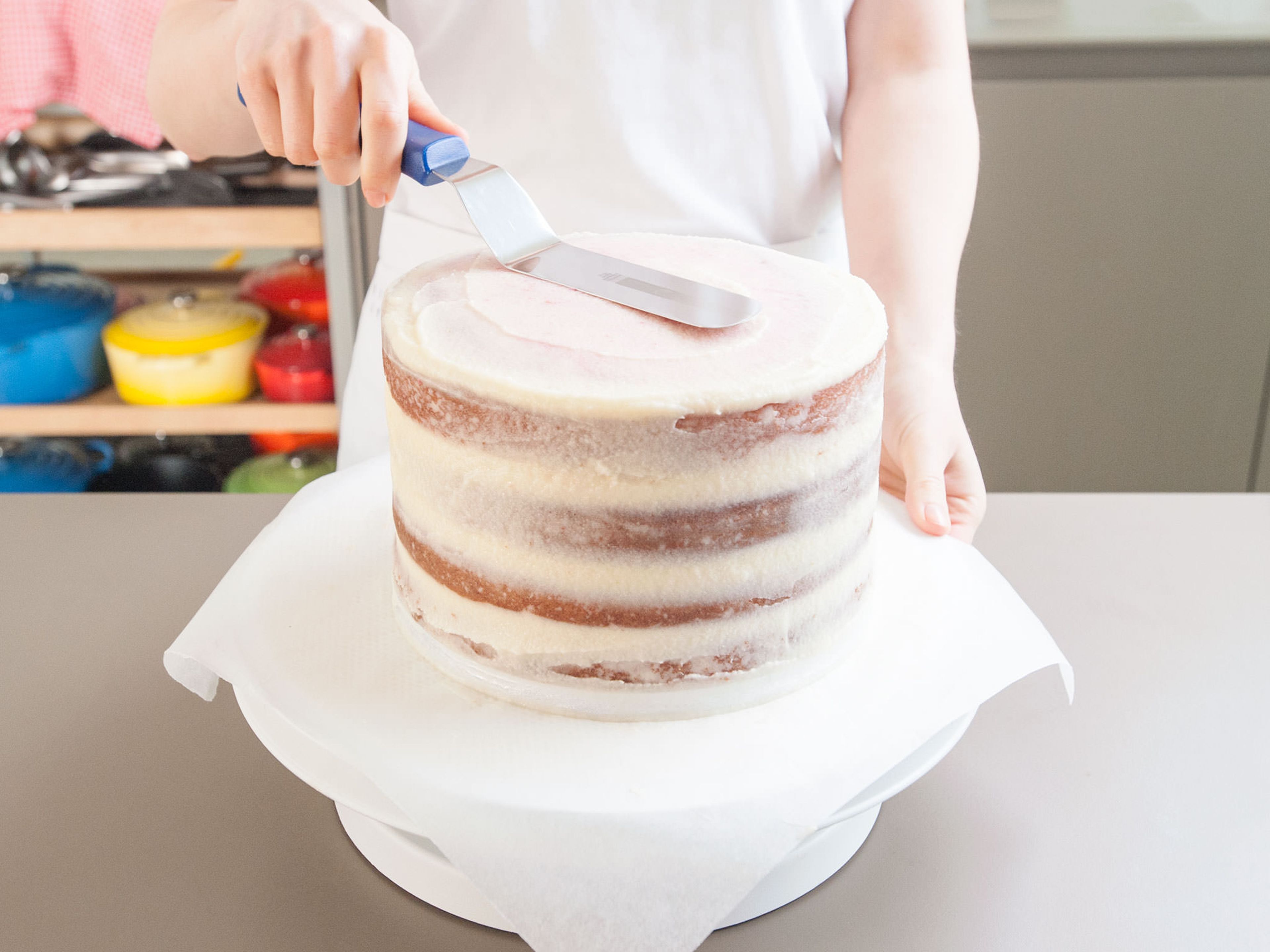Sobald die Torte gekühlt ist, mit der restlichen Buttercreme bestreichen. Einen Teil der Buttercreme aufheben, wenn du später noch etwas auf den Kuchen schreiben möchtest. Nochmals ca. 15 Min. kühlstellen.