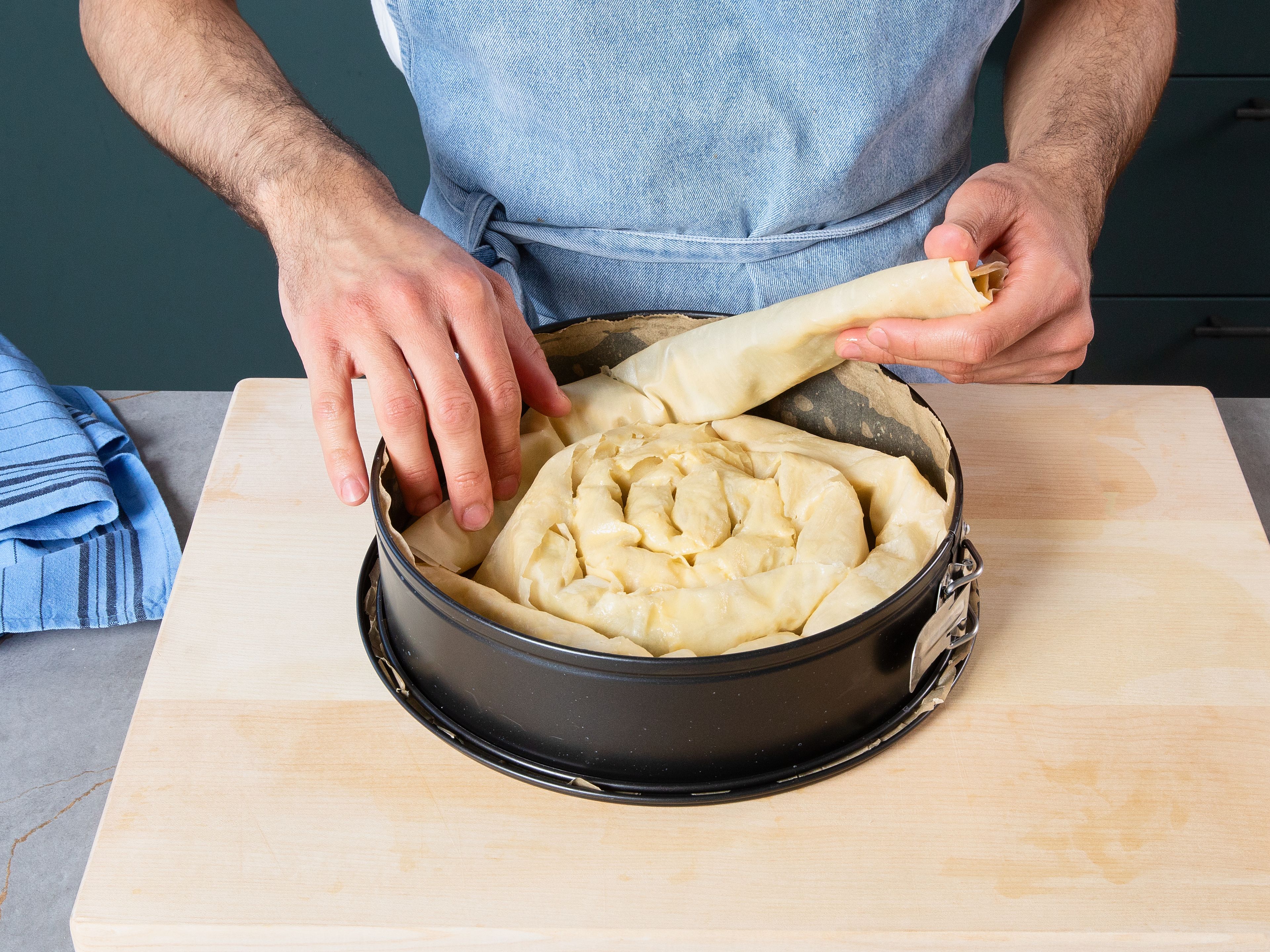 Roll börek into a spiral inside the baking form, starting from the middle. Repeat outward into a big spiral until the form is full. Once the form is covered, brush with more of the wet mix on top. Sprinkle mixed sesame seeds on top and bake for approx. 15–20 min. in the preheated oven until golden and crispy on top. Serve warm or lukewarm.