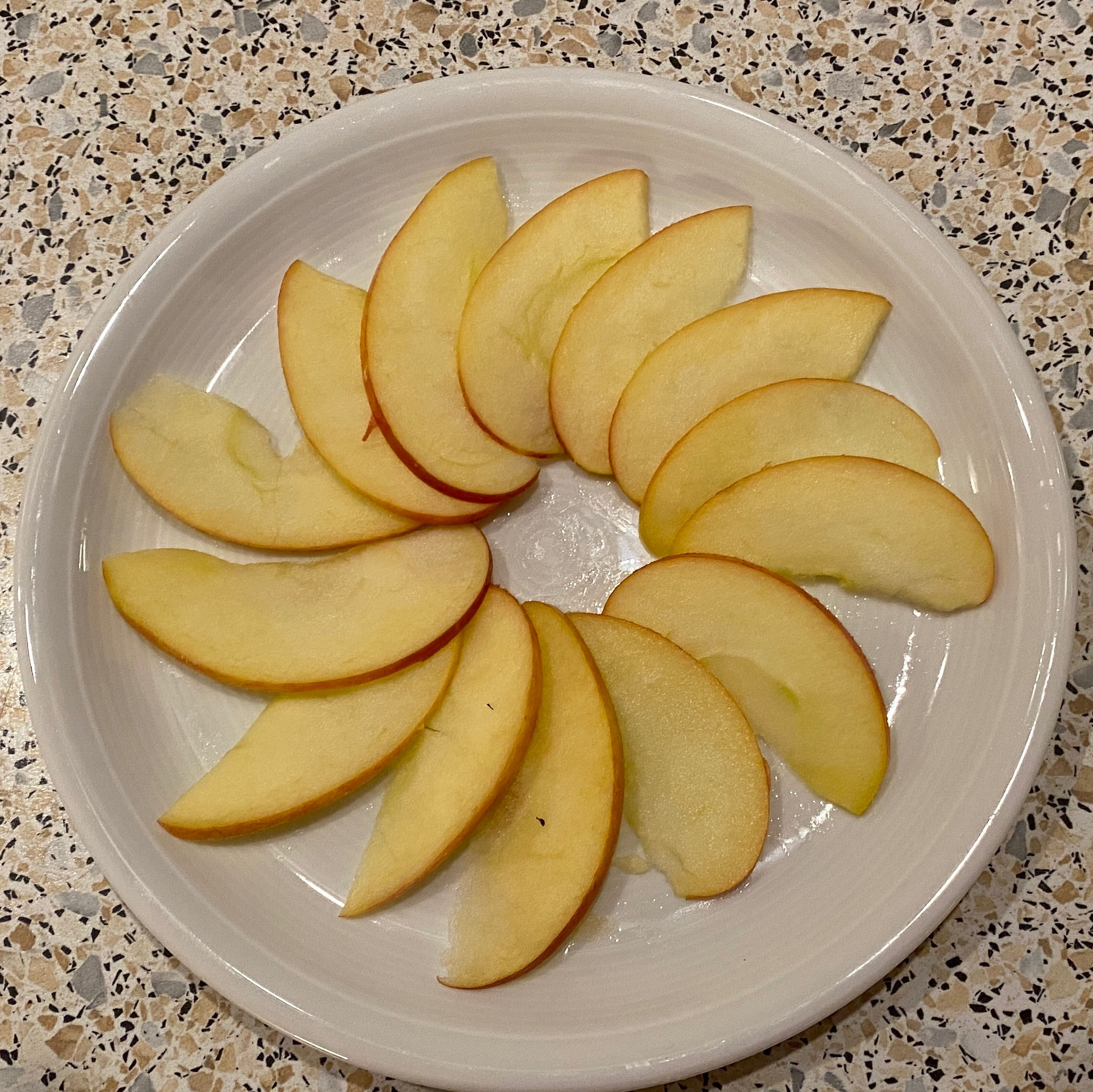 Äpfel in dünne Scheiben schneiden und wie ein Fächer auf den Teller legen.