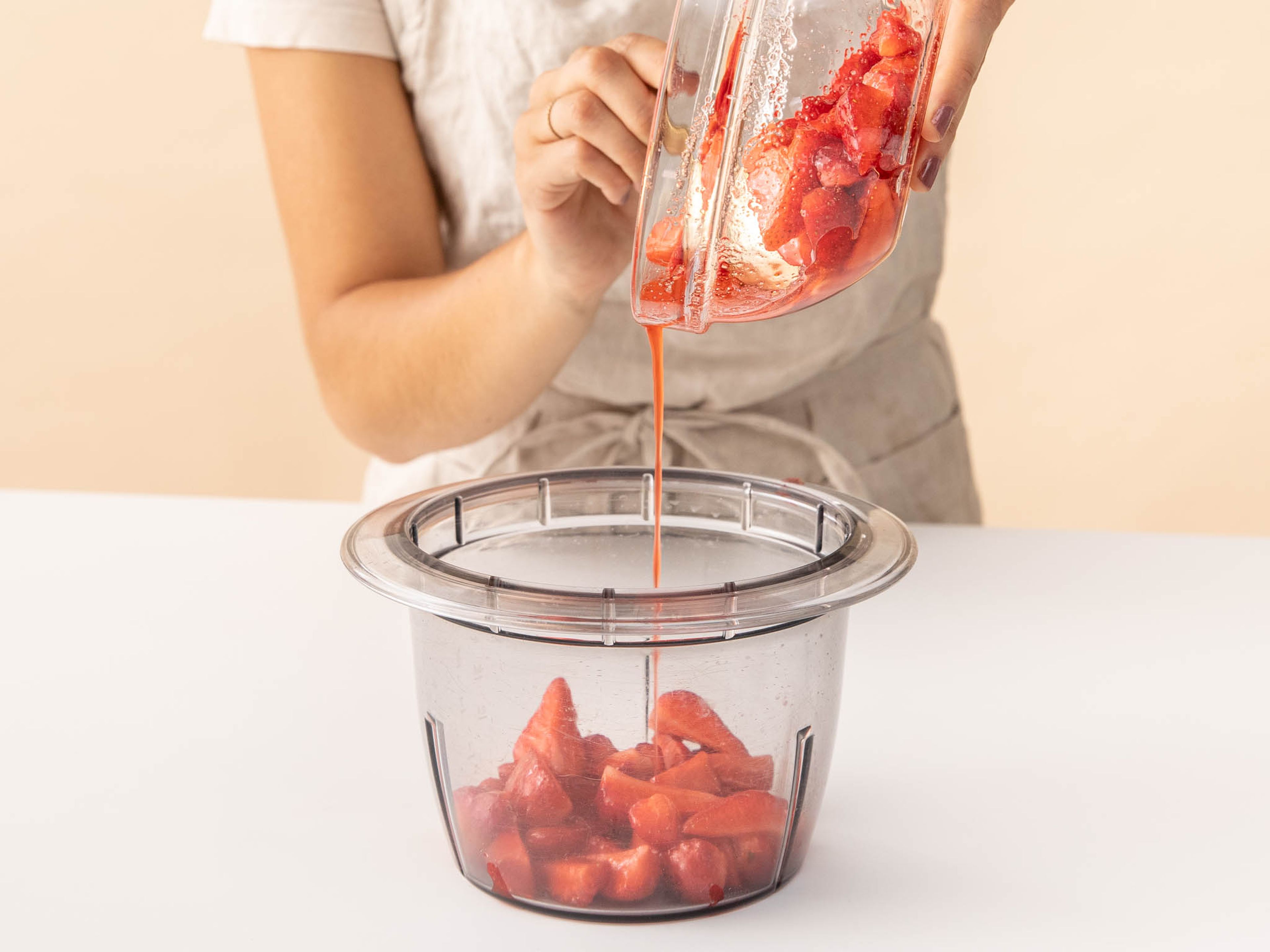 Die Hälfte der Erdbeeren und den gesamten Saft in einen Zerkleinerer geben und pürieren.