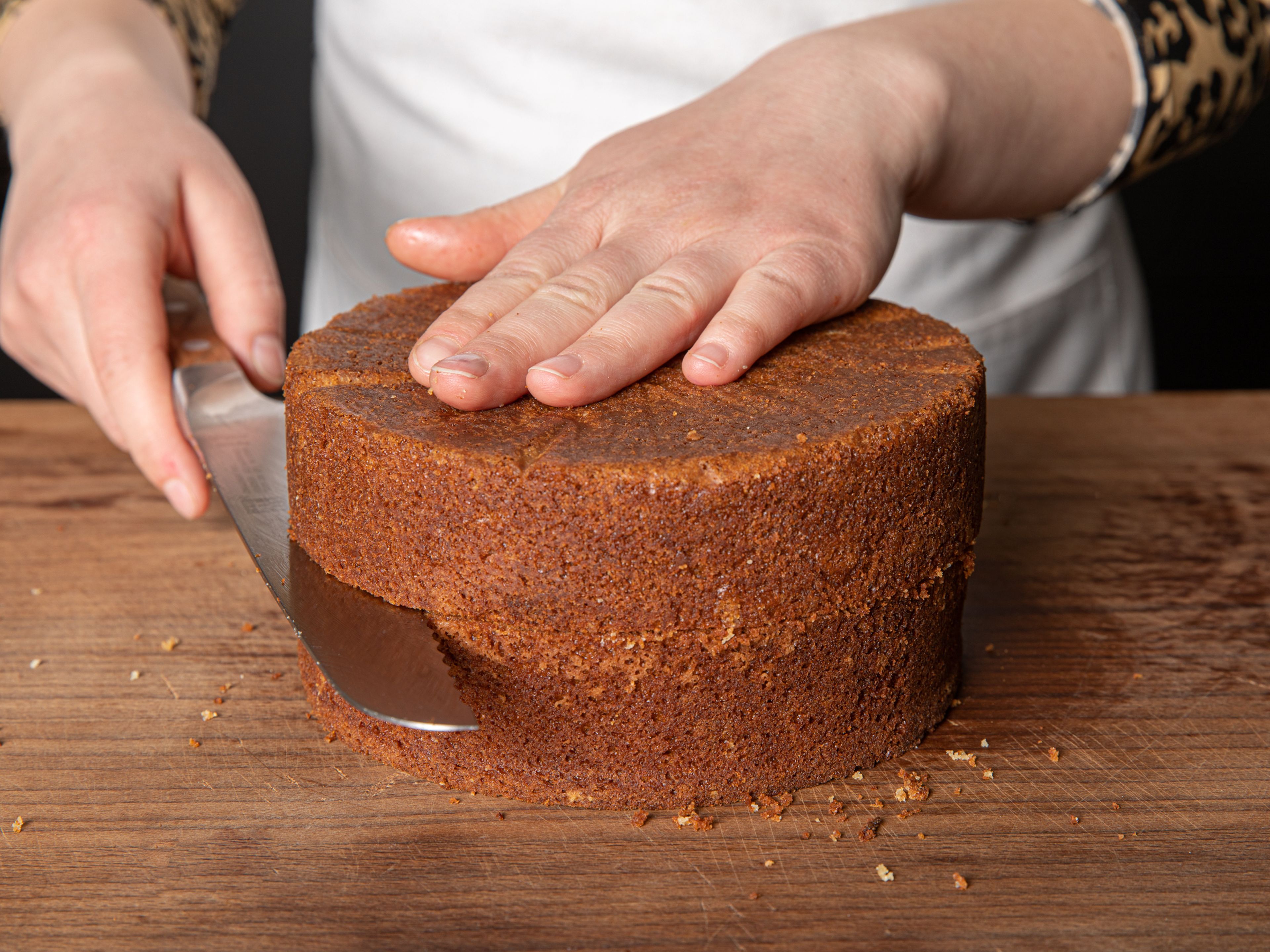 Wenn der Kuchen komplett abgekühlt ist, vorsichtig aus der Form lösen. Wenn der obere Teil nicht komplett gerade ist, mit einem Brotmesser glatt abschneiden. Nun den Boden längs halbieren, so dass zwei gleichmäßige Böden entstehen.